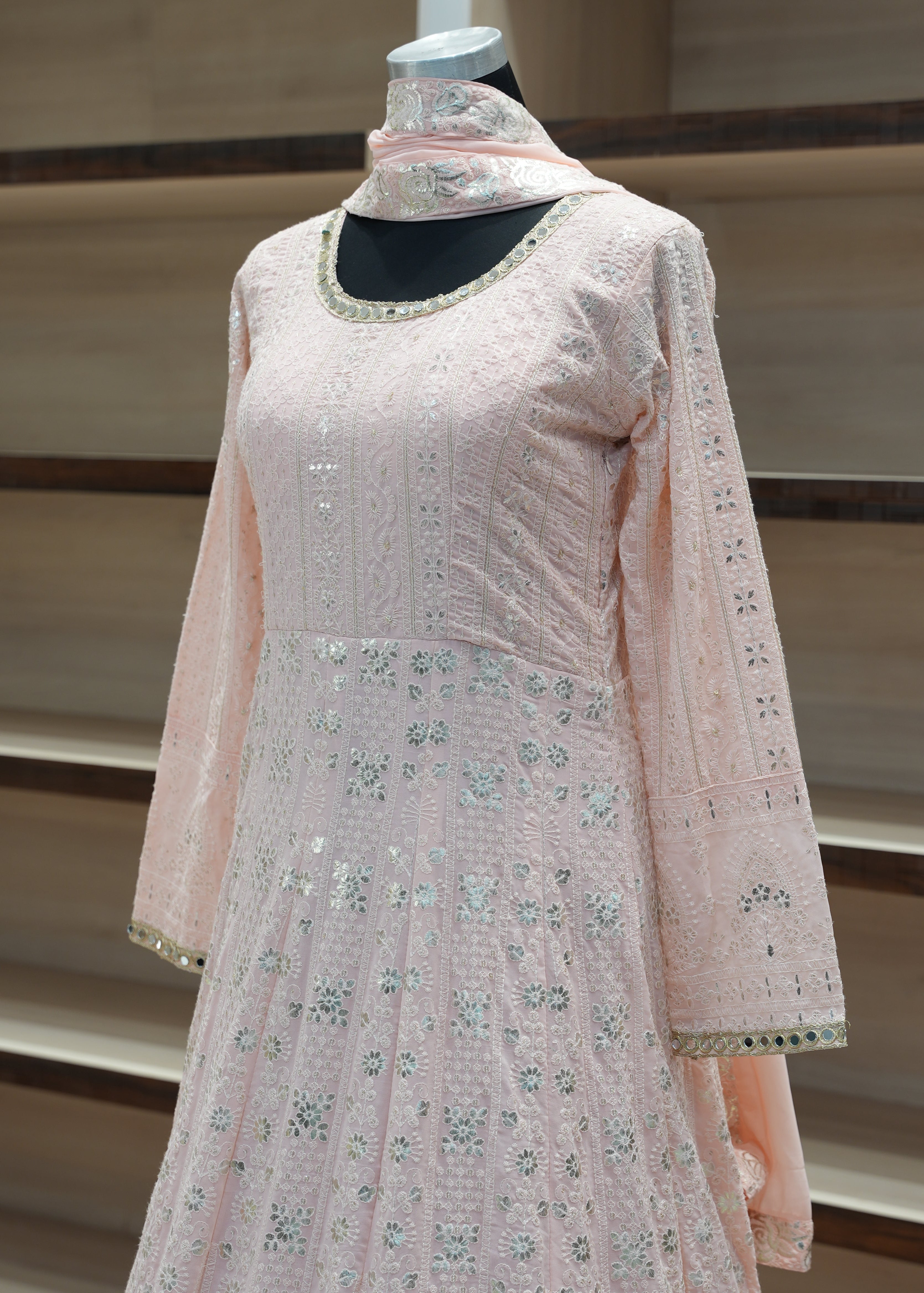 Pink embroidered traditional outfit on a mannequin against a neutral background