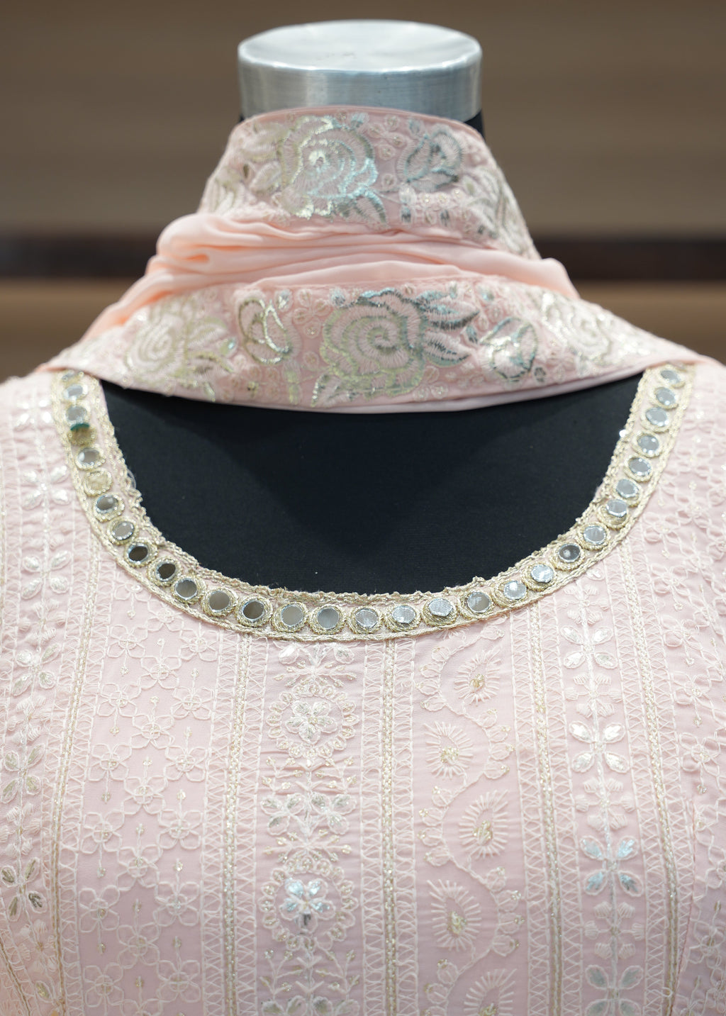 Close-up of a pink embroidered garment on a mannequin with a blurred background