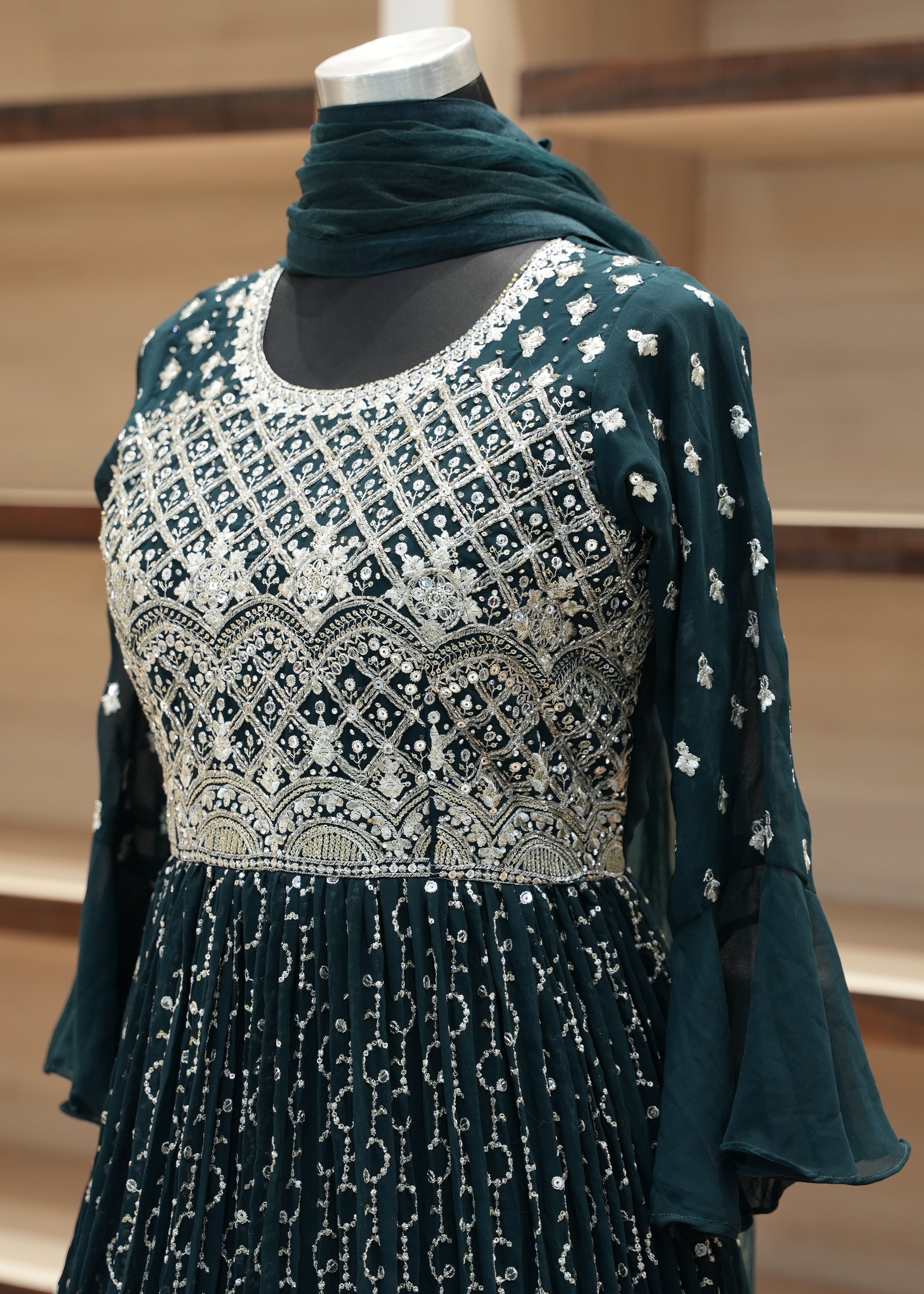 Green dress with intricate silver embroidery on a mannequin against a neutral background