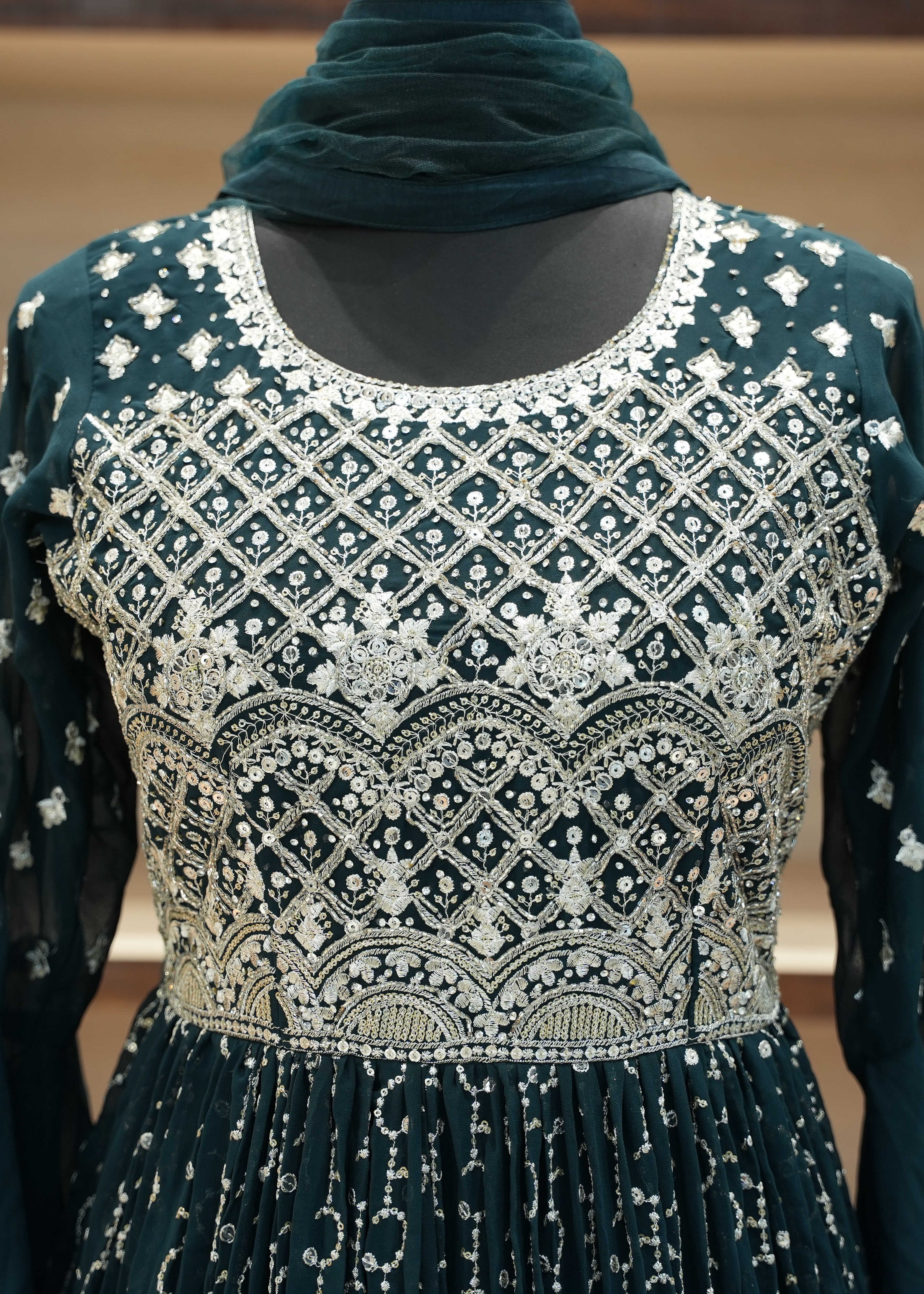 Dark green embroidered dress with a matching scarf on a neutral background