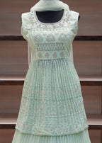 Light green dress with intricate patterns on a wooden background