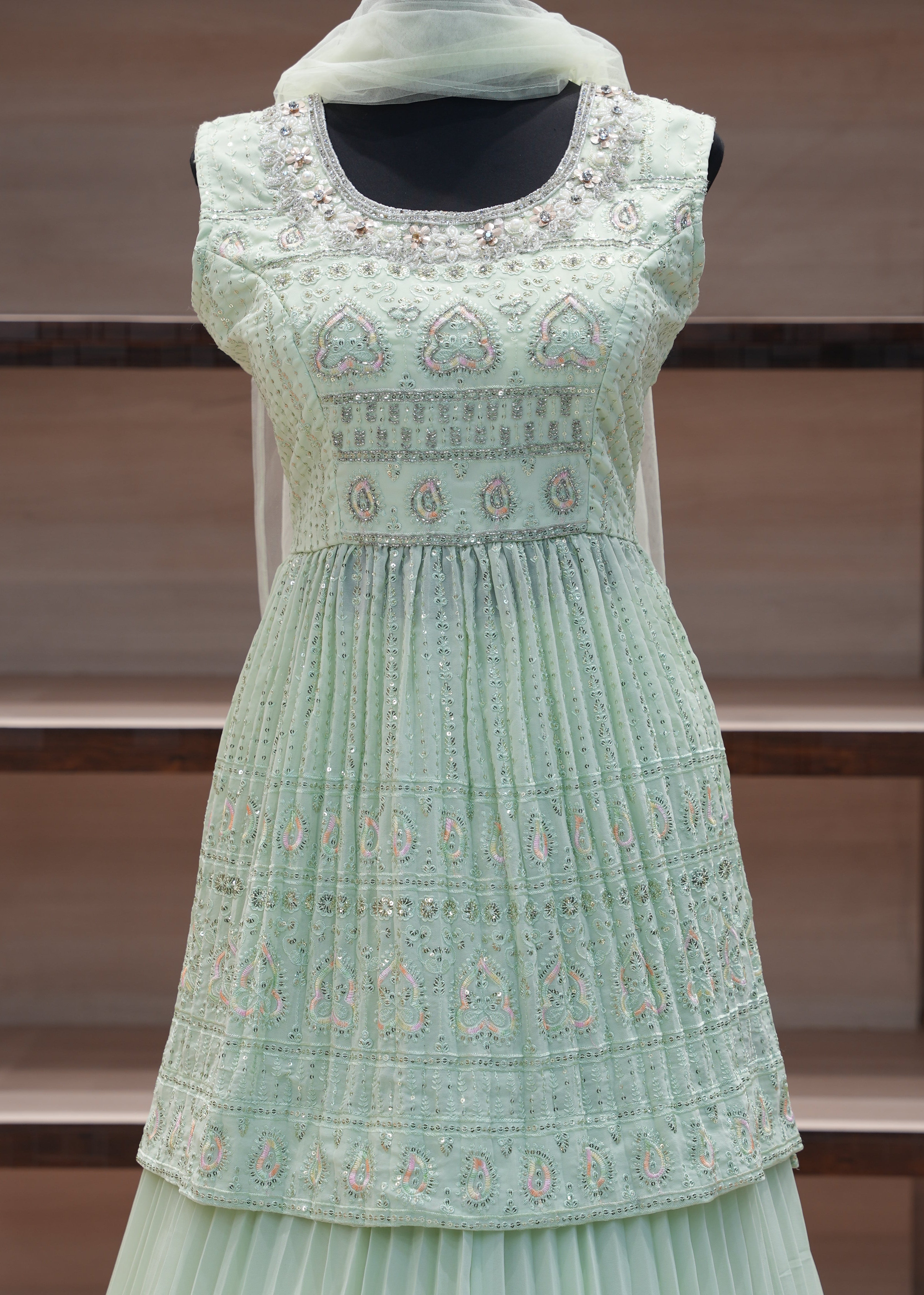 Light green dress with intricate patterns on a wooden background
