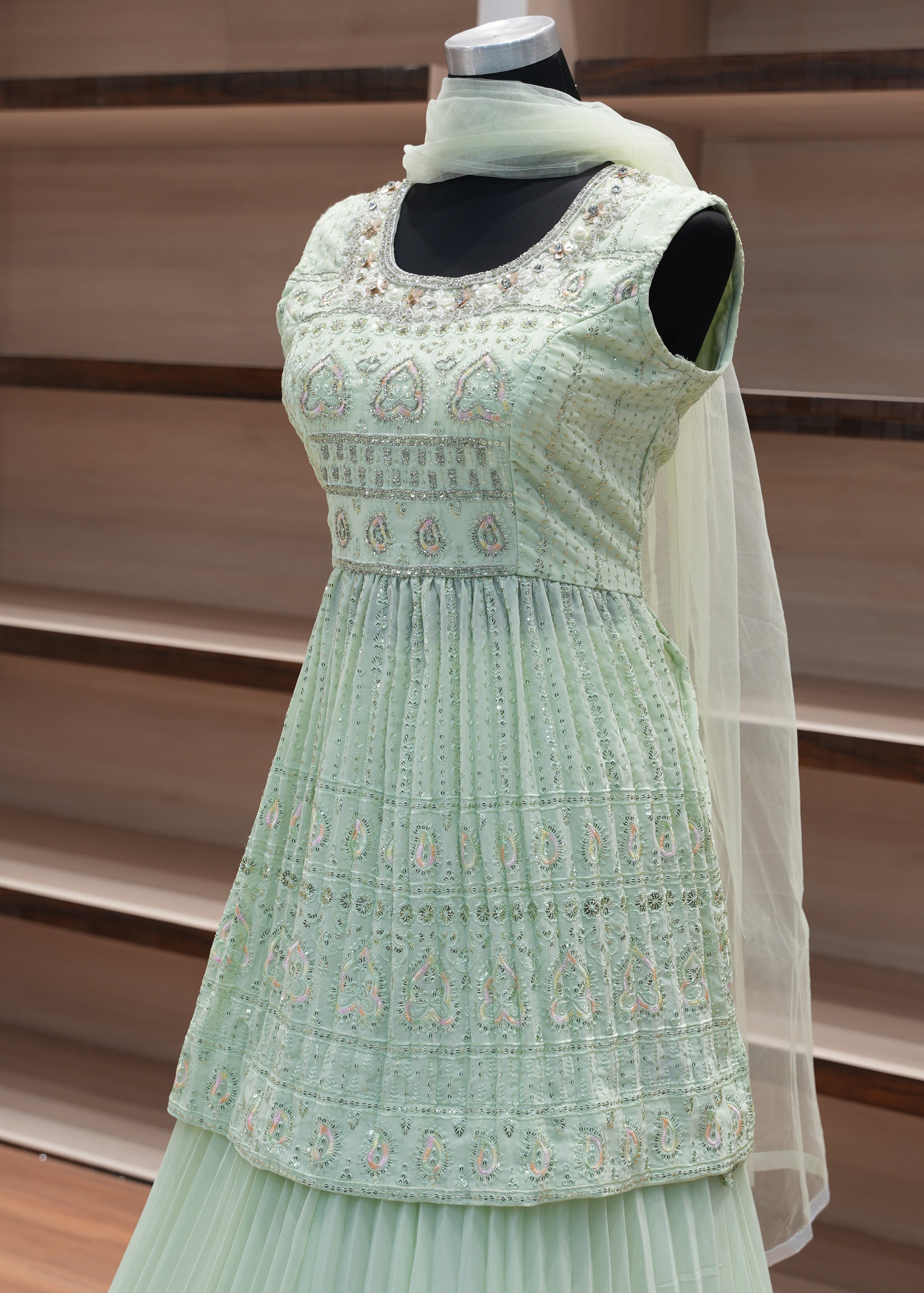 Green embroidered dress on a mannequin against a wooden panel background