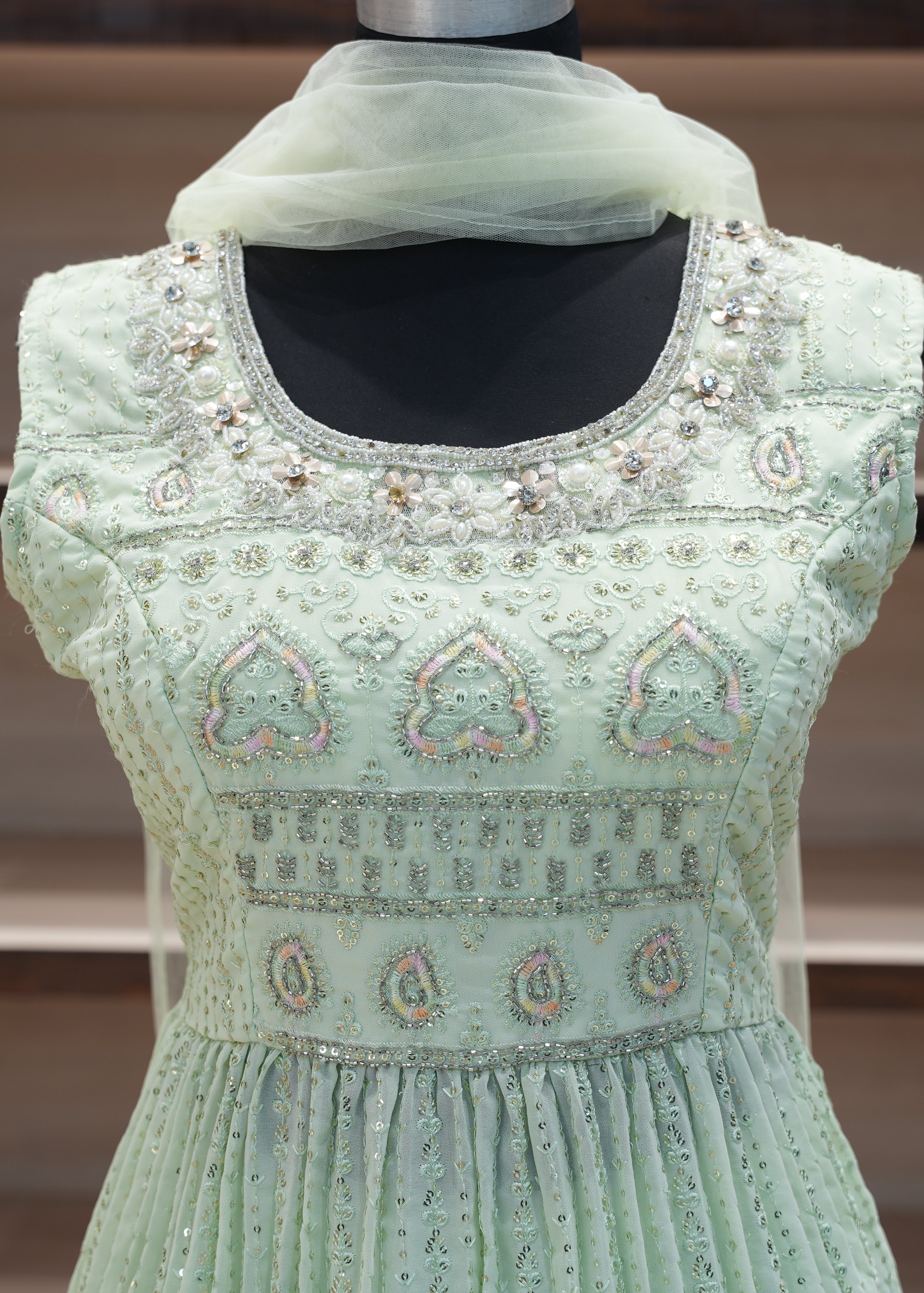 Light green embroidered dress on a mannequin with a blurred background