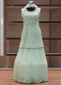 Light green pleated dress on a mannequin against a wooden panel background