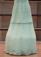 Light green pleated skirt with floral pattern on a wooden chair.