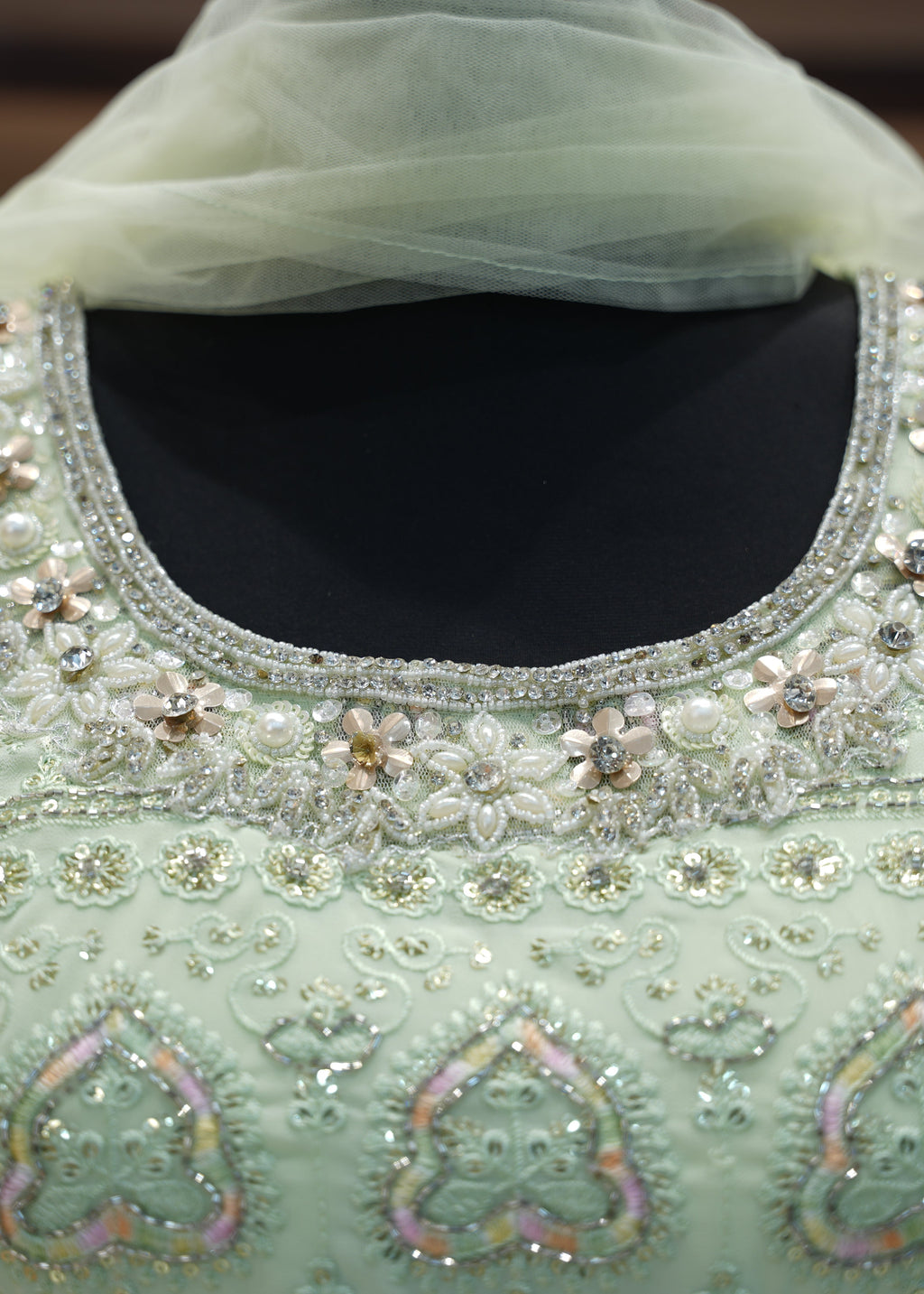 Light green embroidered garment with intricate patterns and embellishments.