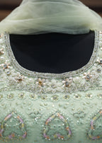 Light green embroidered garment with intricate patterns and embellishments.