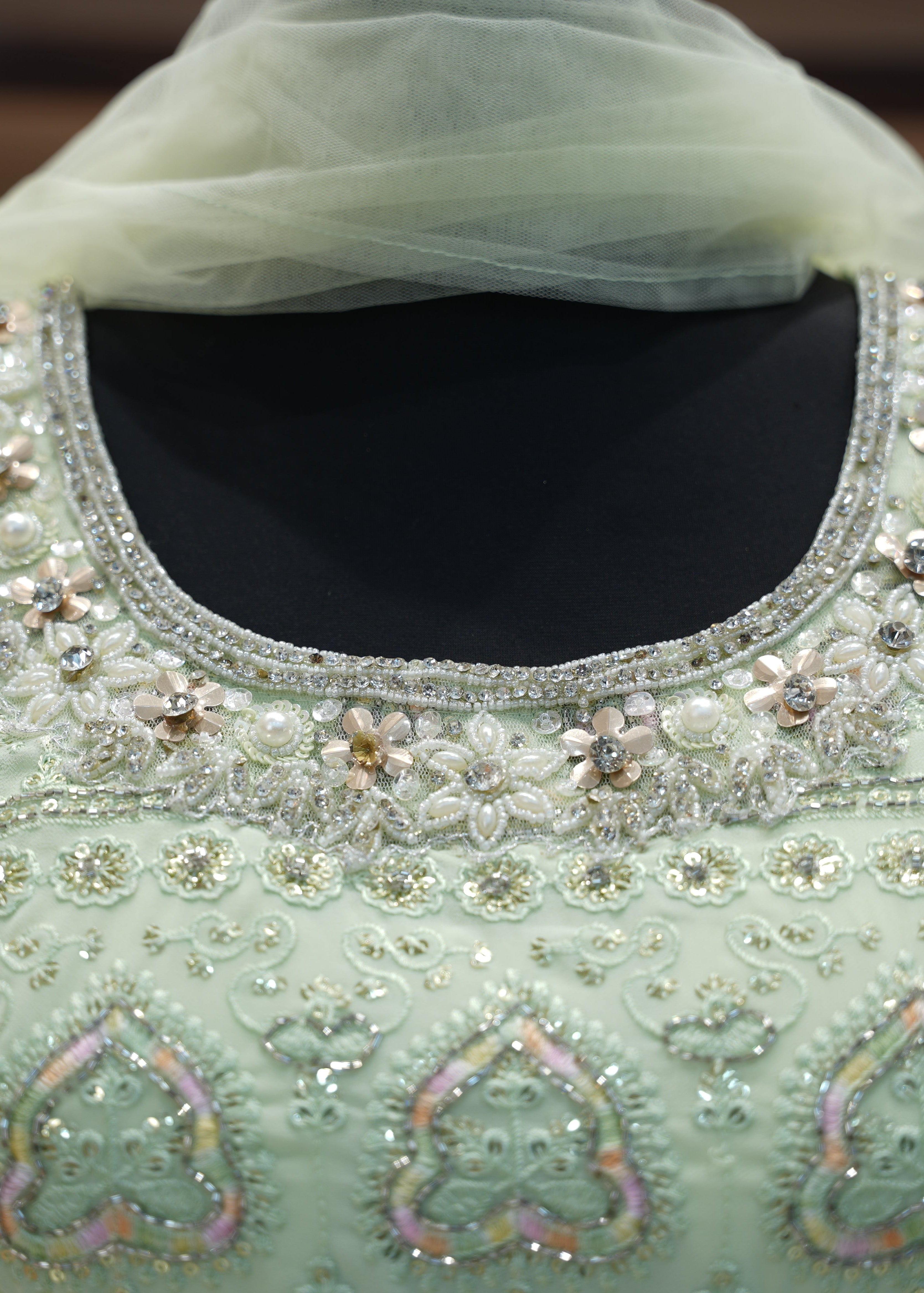 Light green embroidered garment with intricate patterns and embellishments.