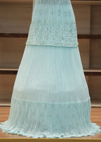 Light blue pleated fabric draped over a chair with a wooden background