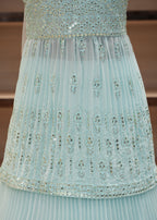 Light blue dress with floral embroidery on a wooden shelf background