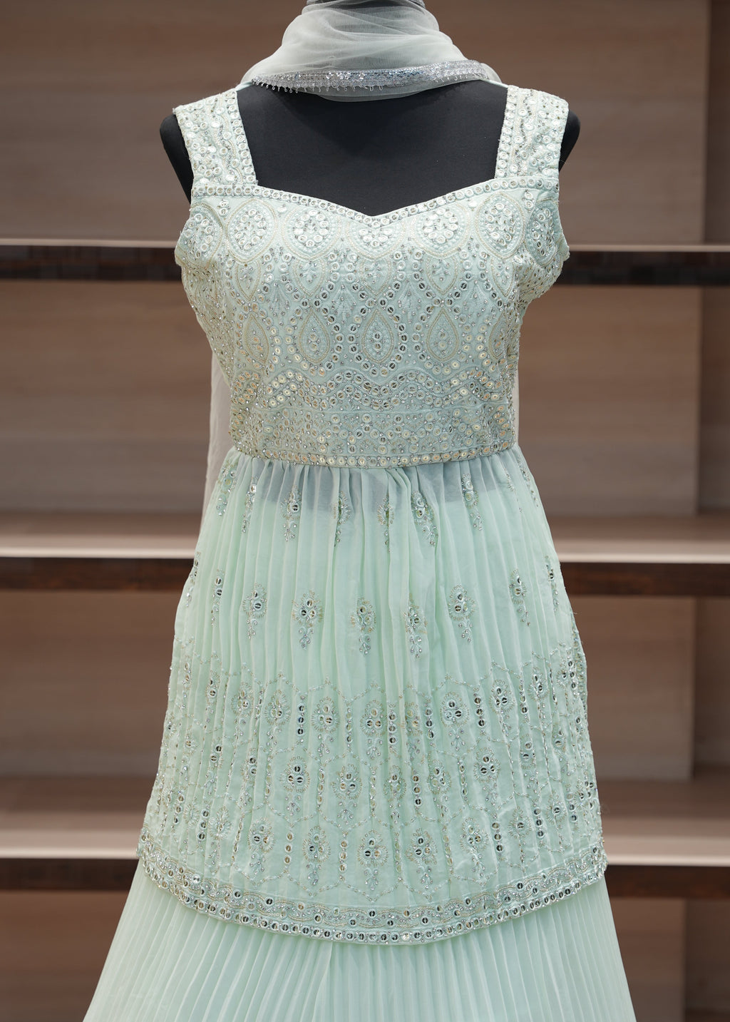 Light blue dress with decorative elements on a mannequin against a wooden panel background