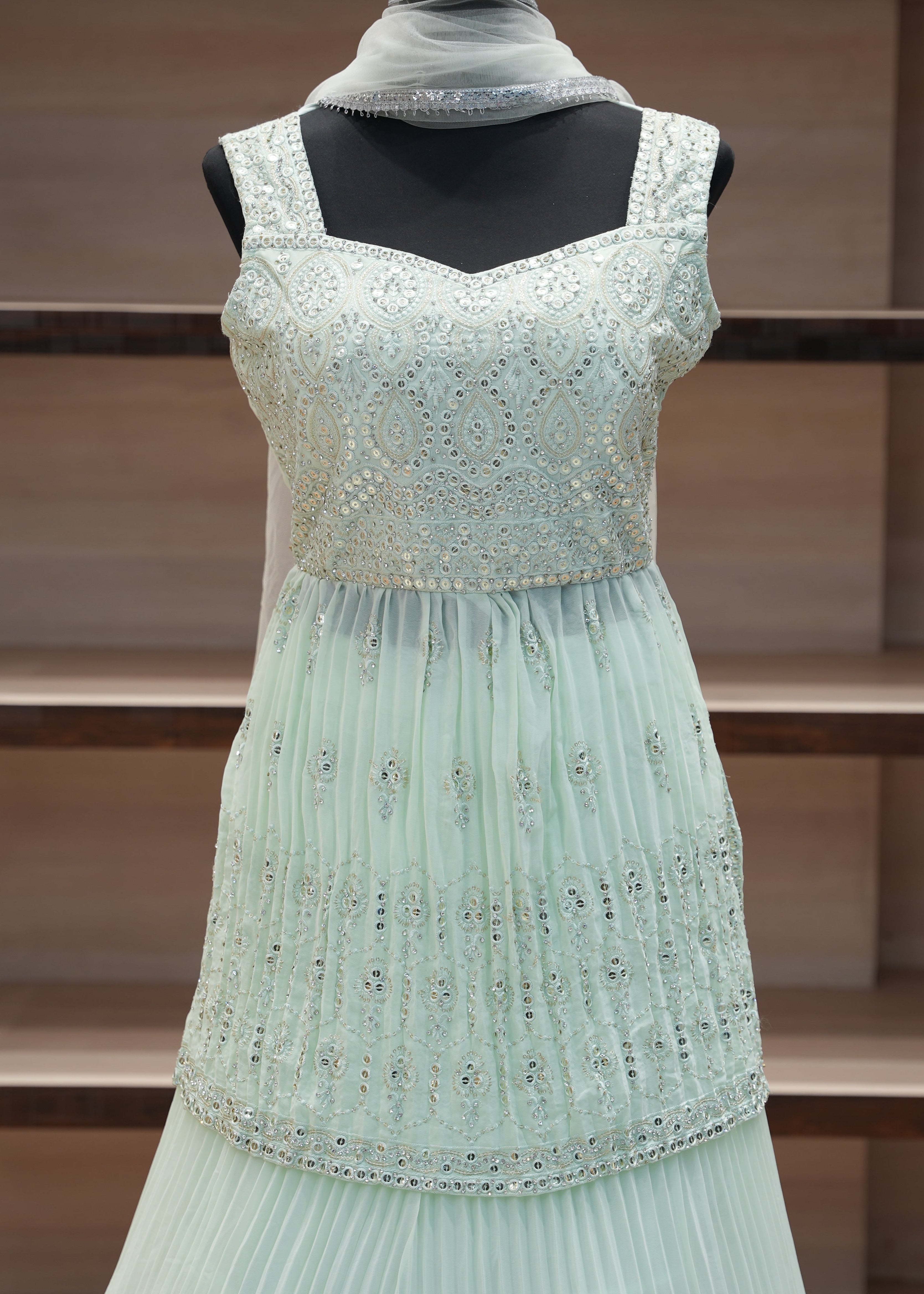 Light blue dress with decorative elements on a mannequin against a wooden panel background