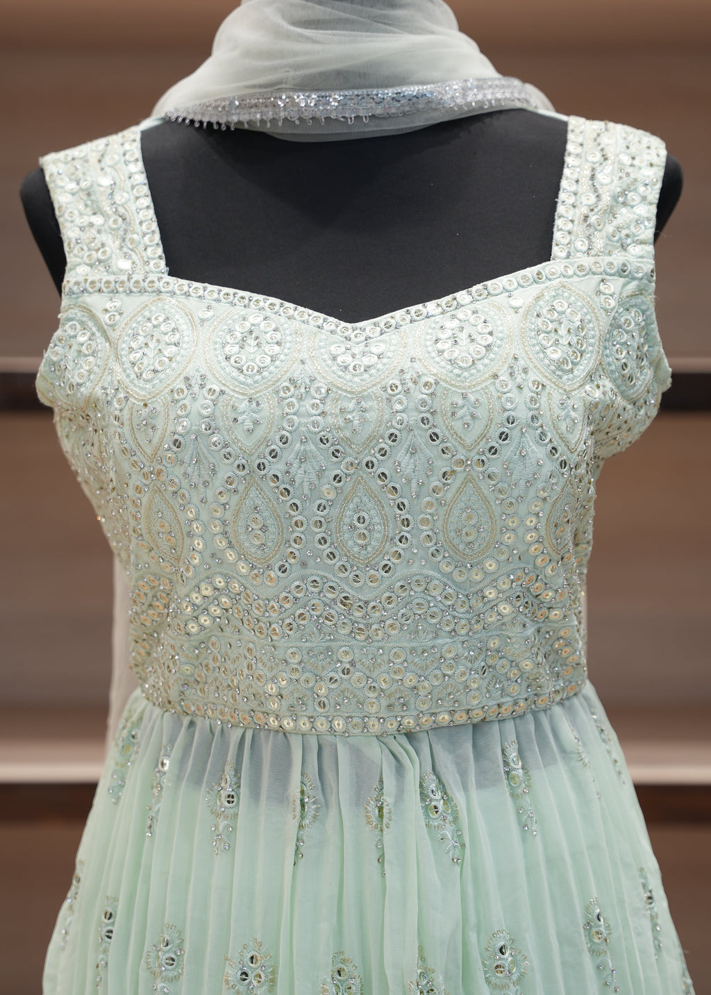 Light blue evening gown with intricate detailing on a mannequin against a blurred background