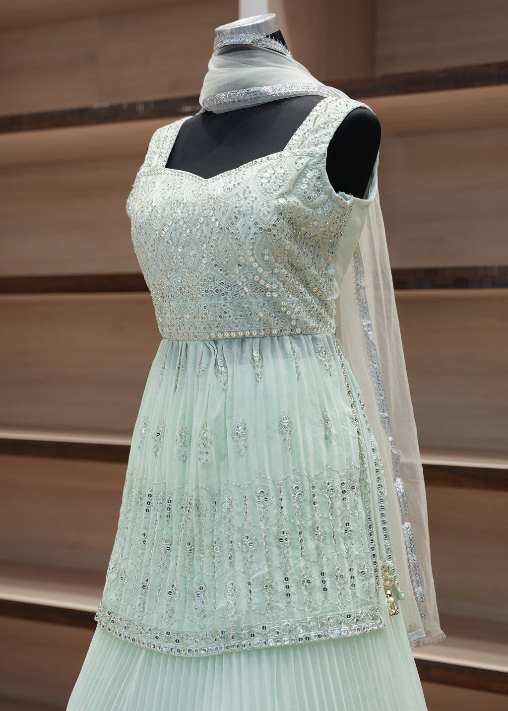 Light green dress with glittery details on a mannequin against a neutral background