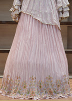 Close-up of a pink pleated fabric with floral embroidery on a wooden surface.