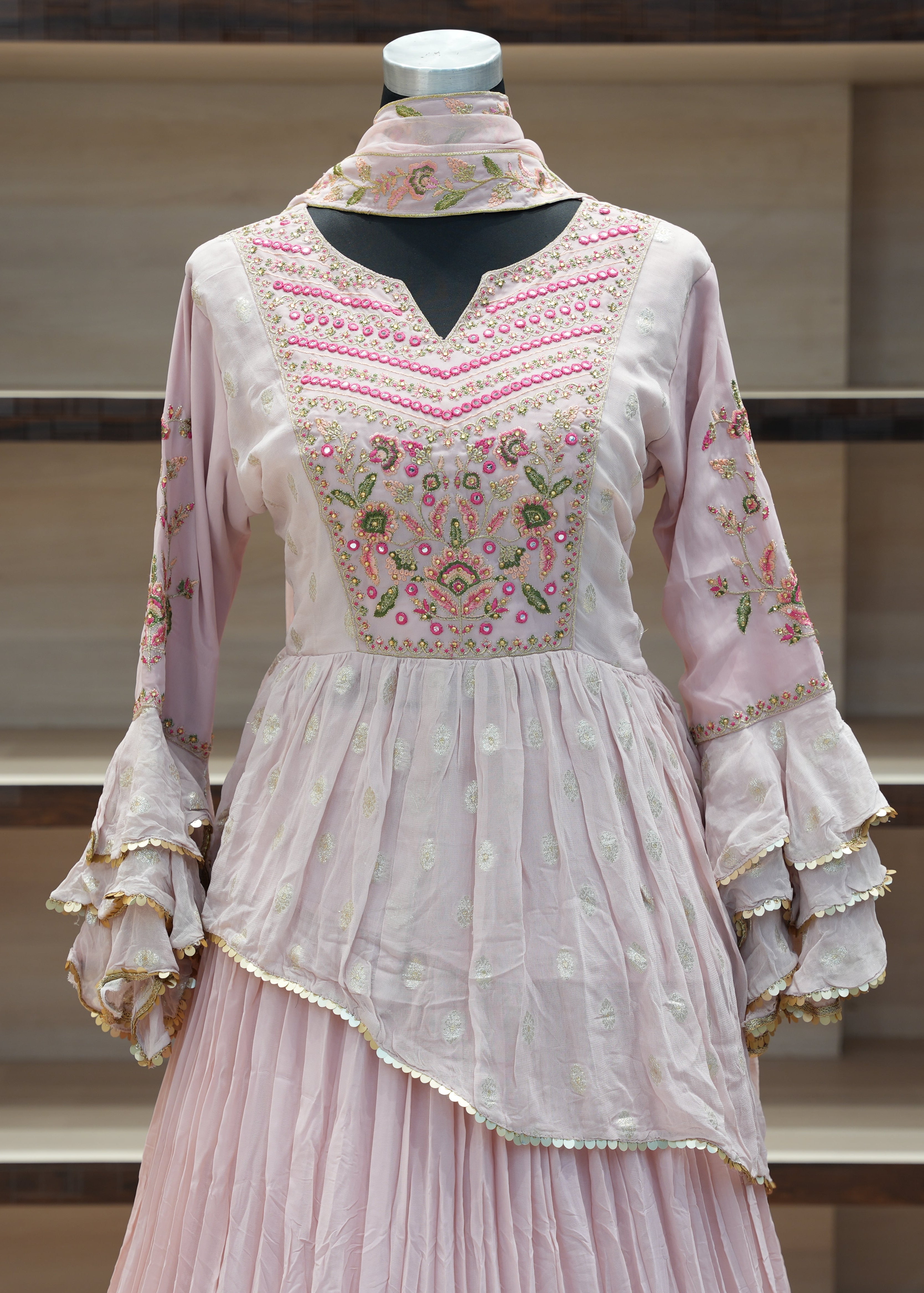 Pink embroidered traditional outfit on a mannequin against a neutral background