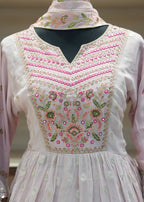 White embroidered dress with pink embellishments on a neutral background
