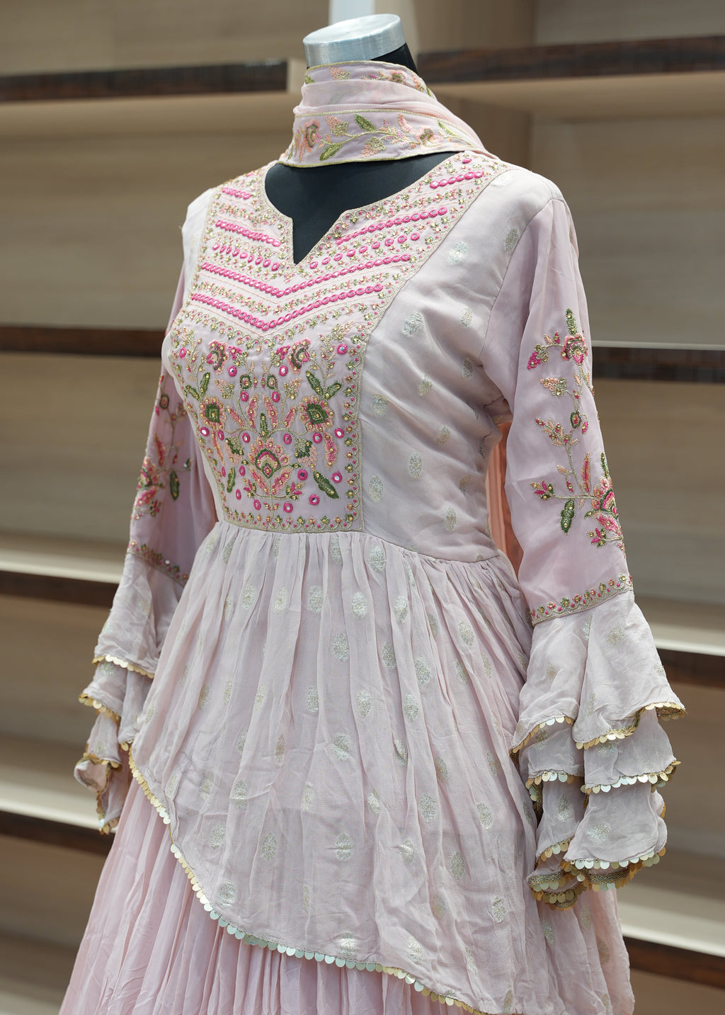 Pink embroidered dress on a mannequin against a neutral background