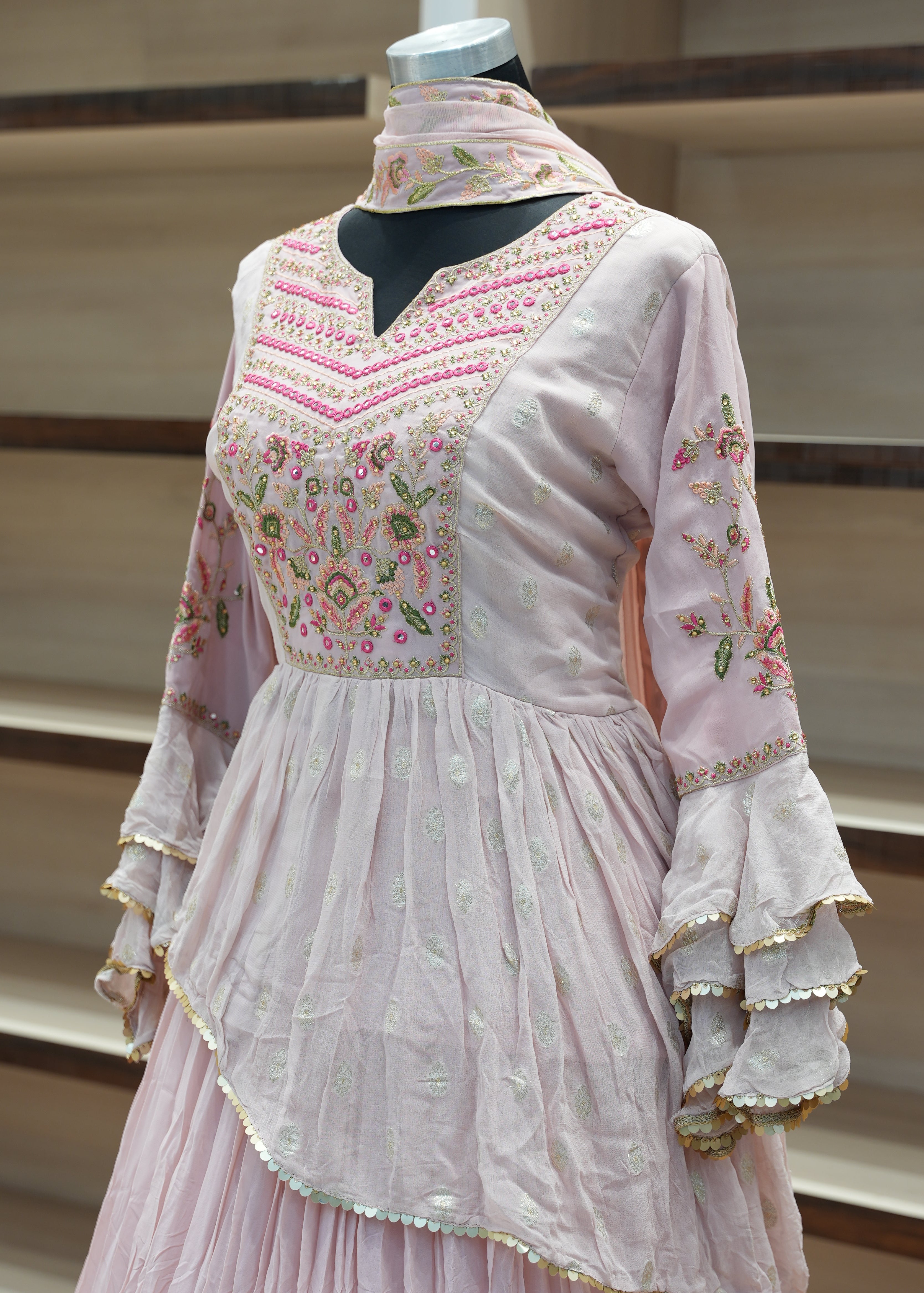 Pink embroidered dress on a mannequin against a neutral background