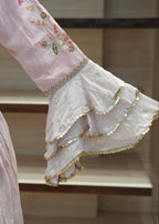 Close-up of a pink embroidered garment with ruffled details.