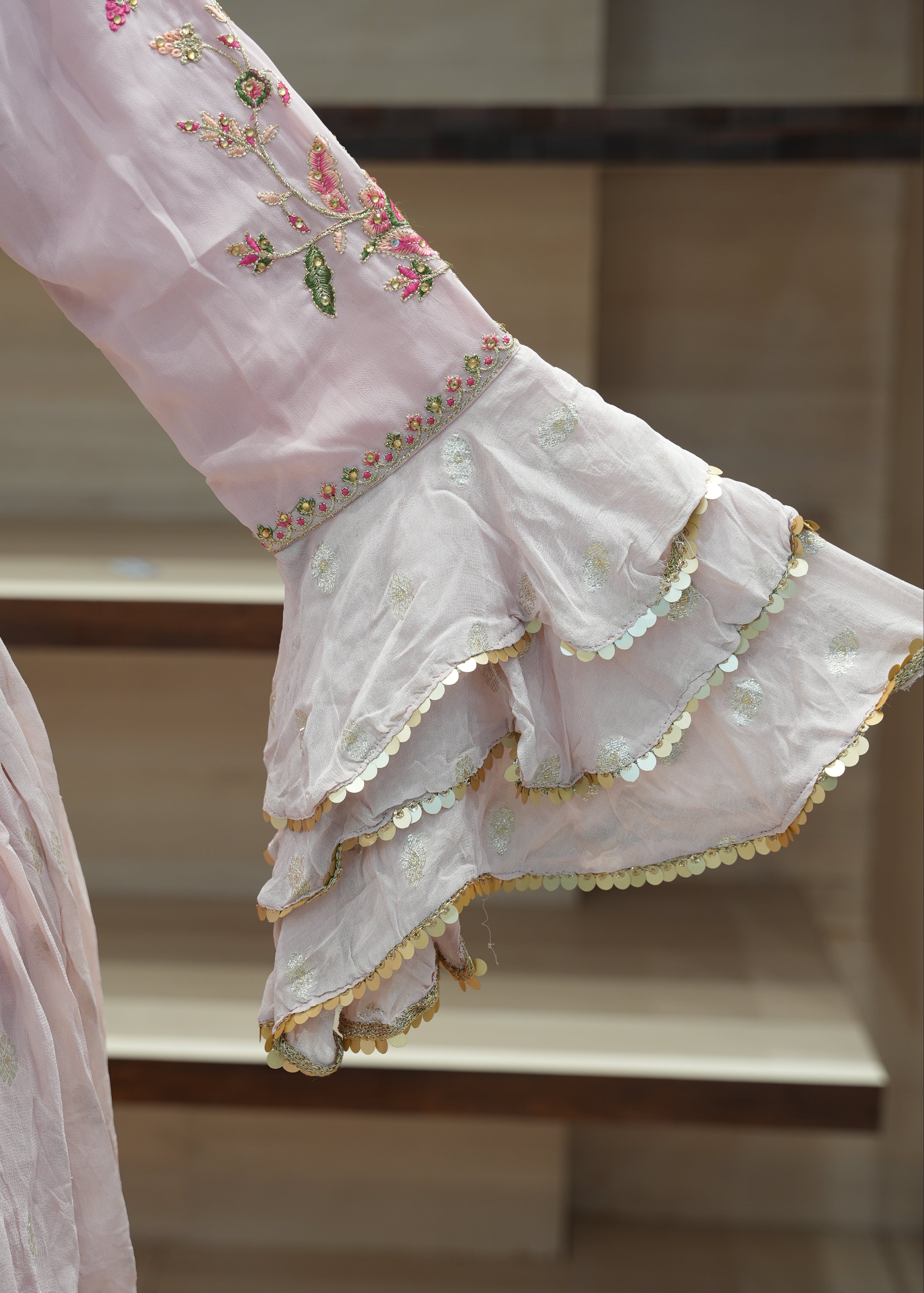 Close-up of a pink embroidered garment with ruffled details.