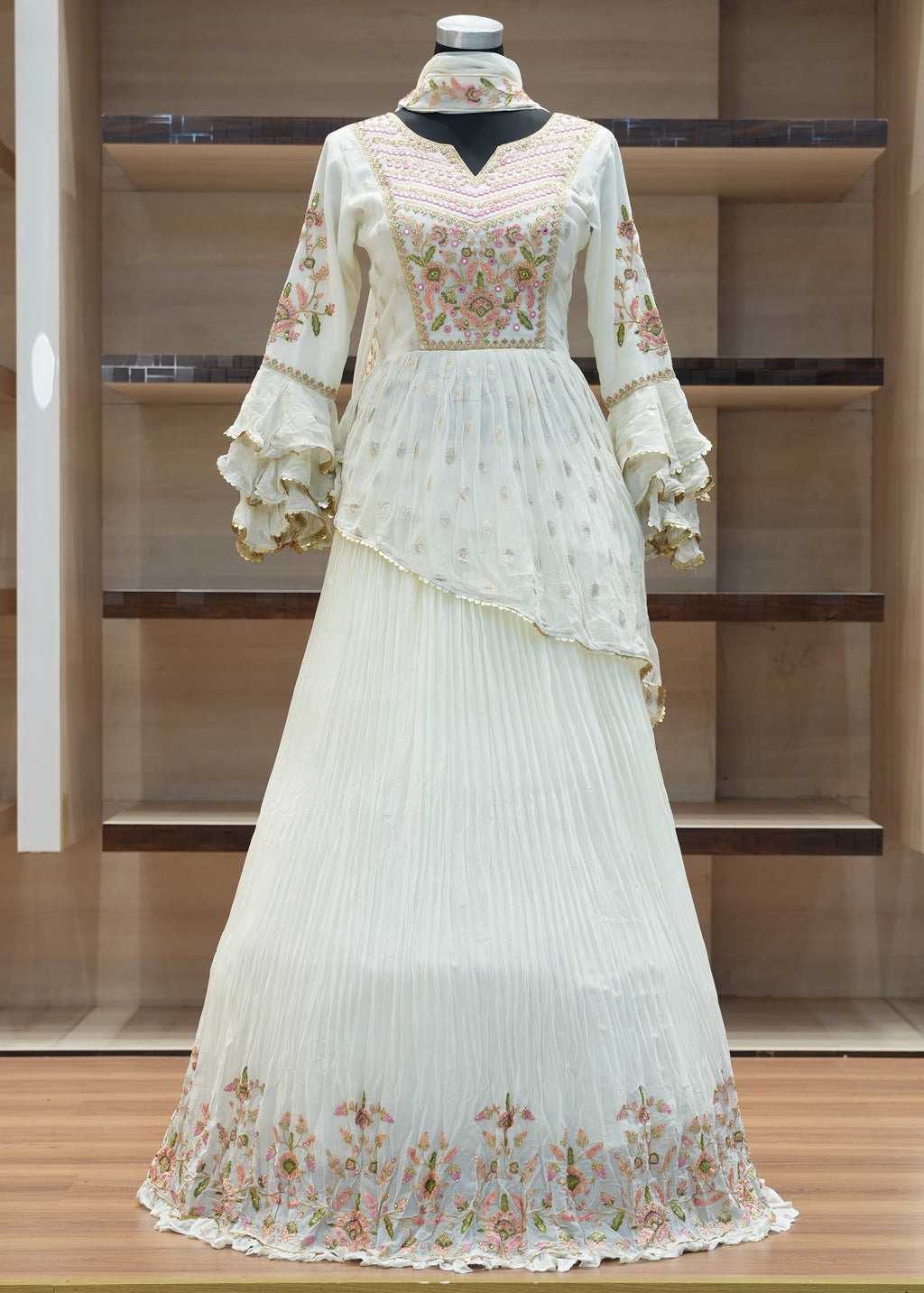 White dress with floral patterns on a mannequin against a wooden panel background