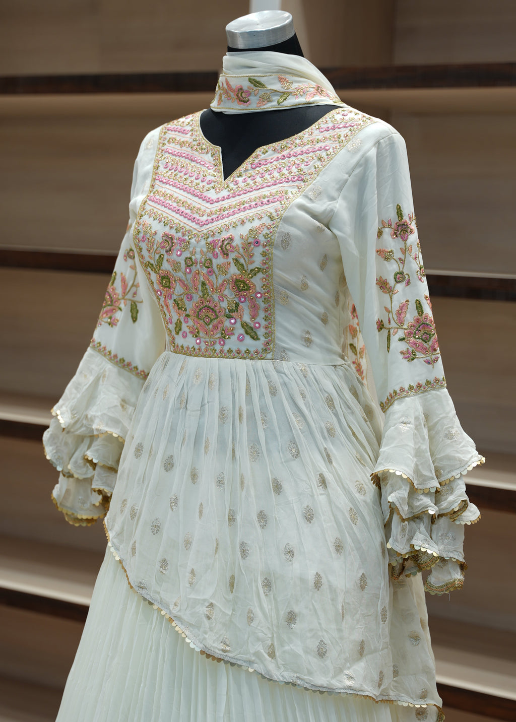 Decorative white garment with floral embroidery on a wooden stand.