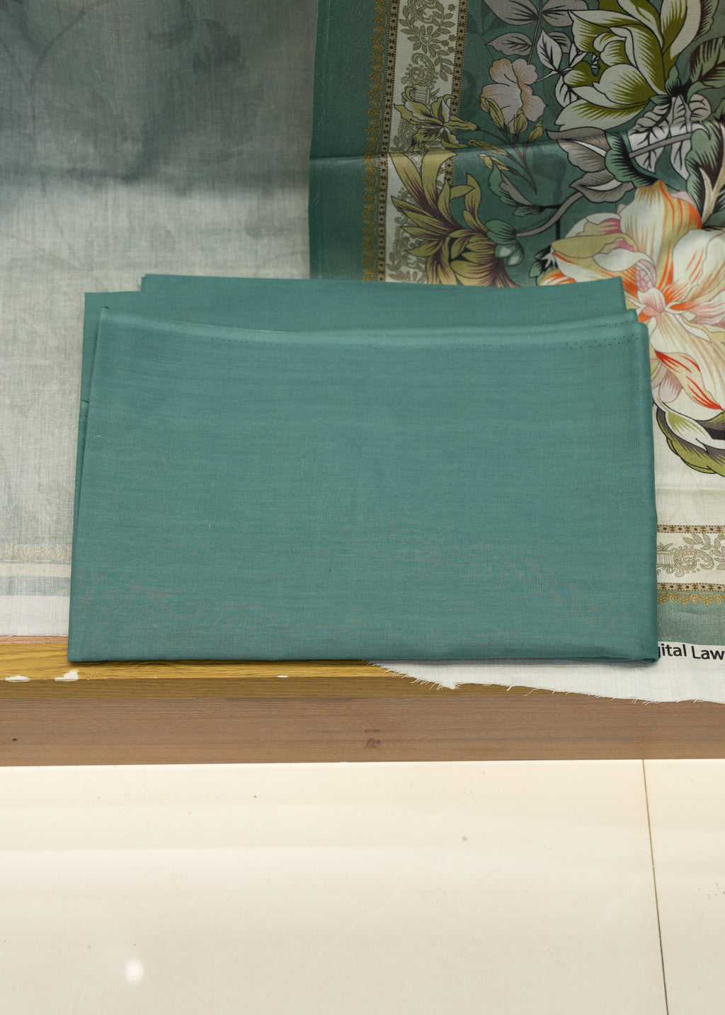 Teal fabric with floral patterned fabric in the background