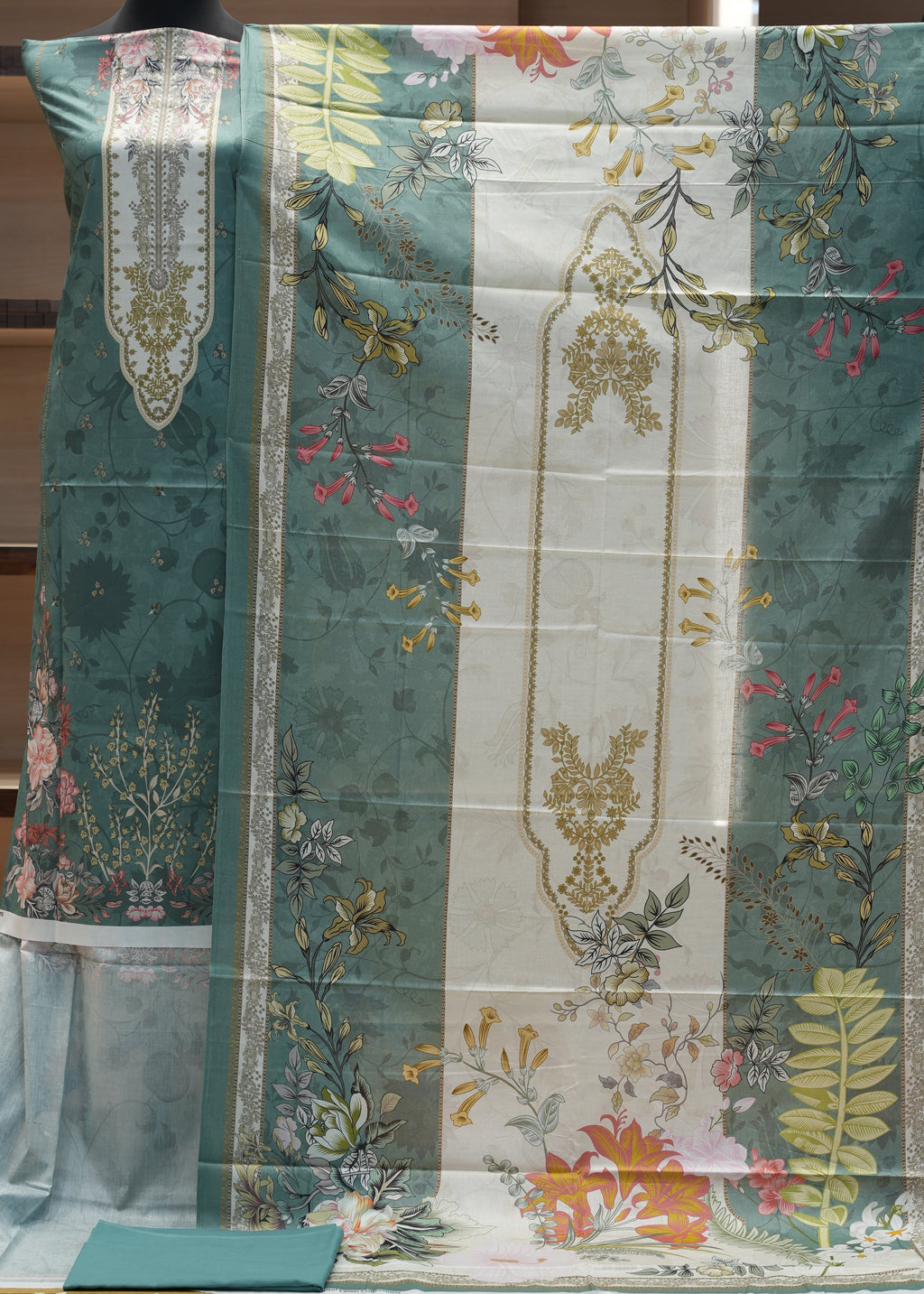 Floral patterned fabric with green, white, and multicolor design on a wooden background