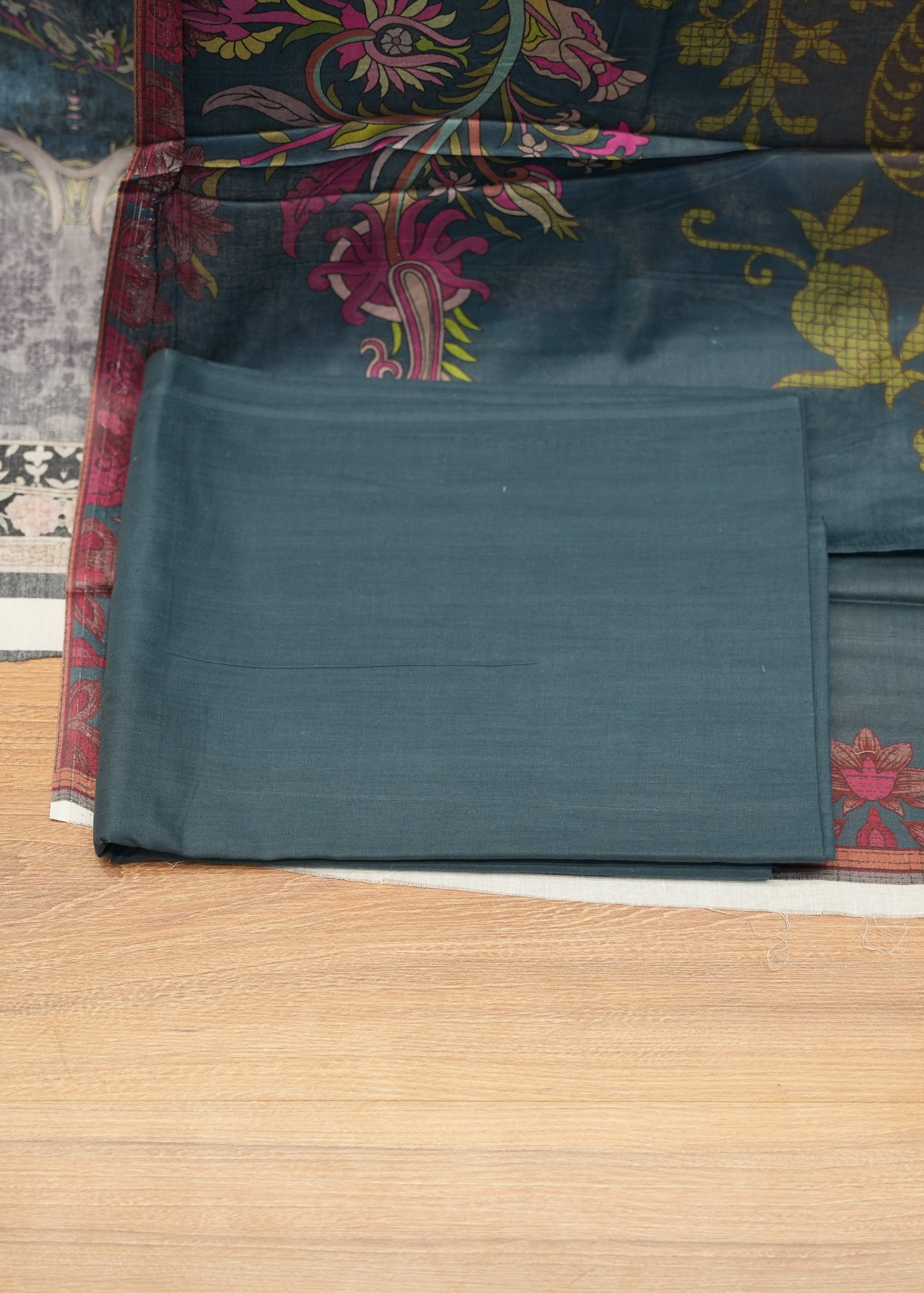 Teal fabric with floral patterns on a wooden floor