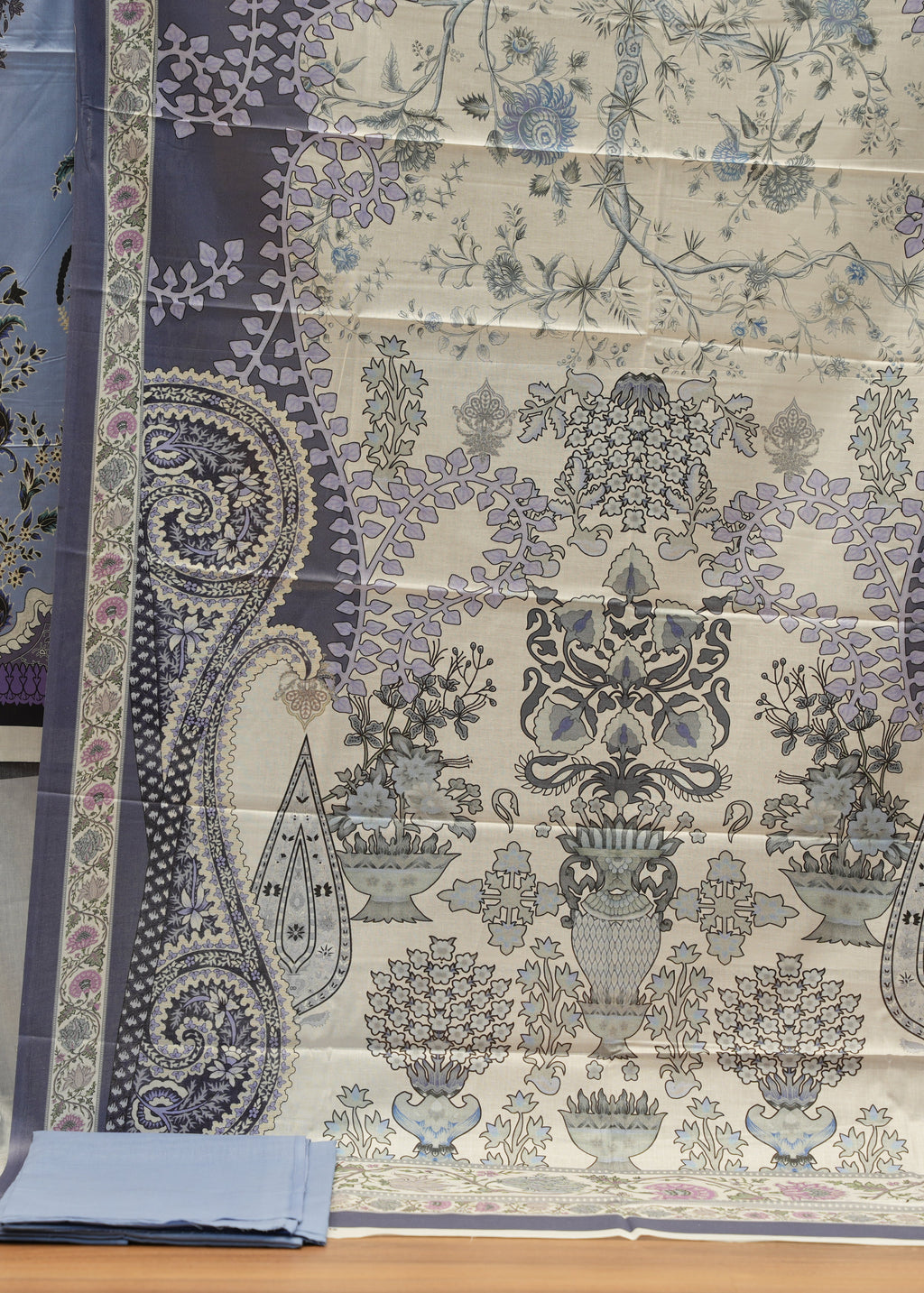 Decorative fabric with paisley and floral patterns on a wooden surface