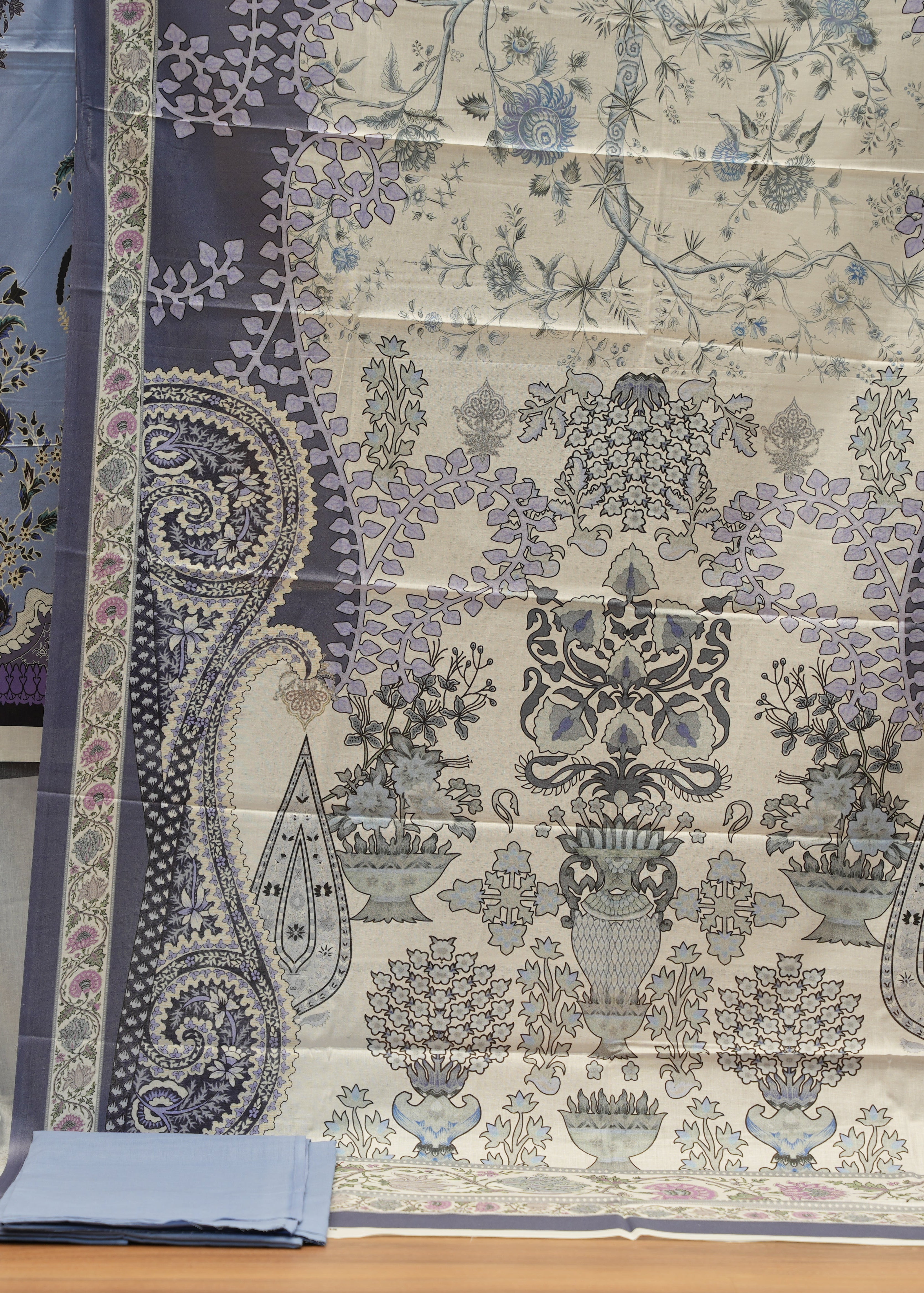 Decorative fabric with paisley and floral patterns on a wooden surface