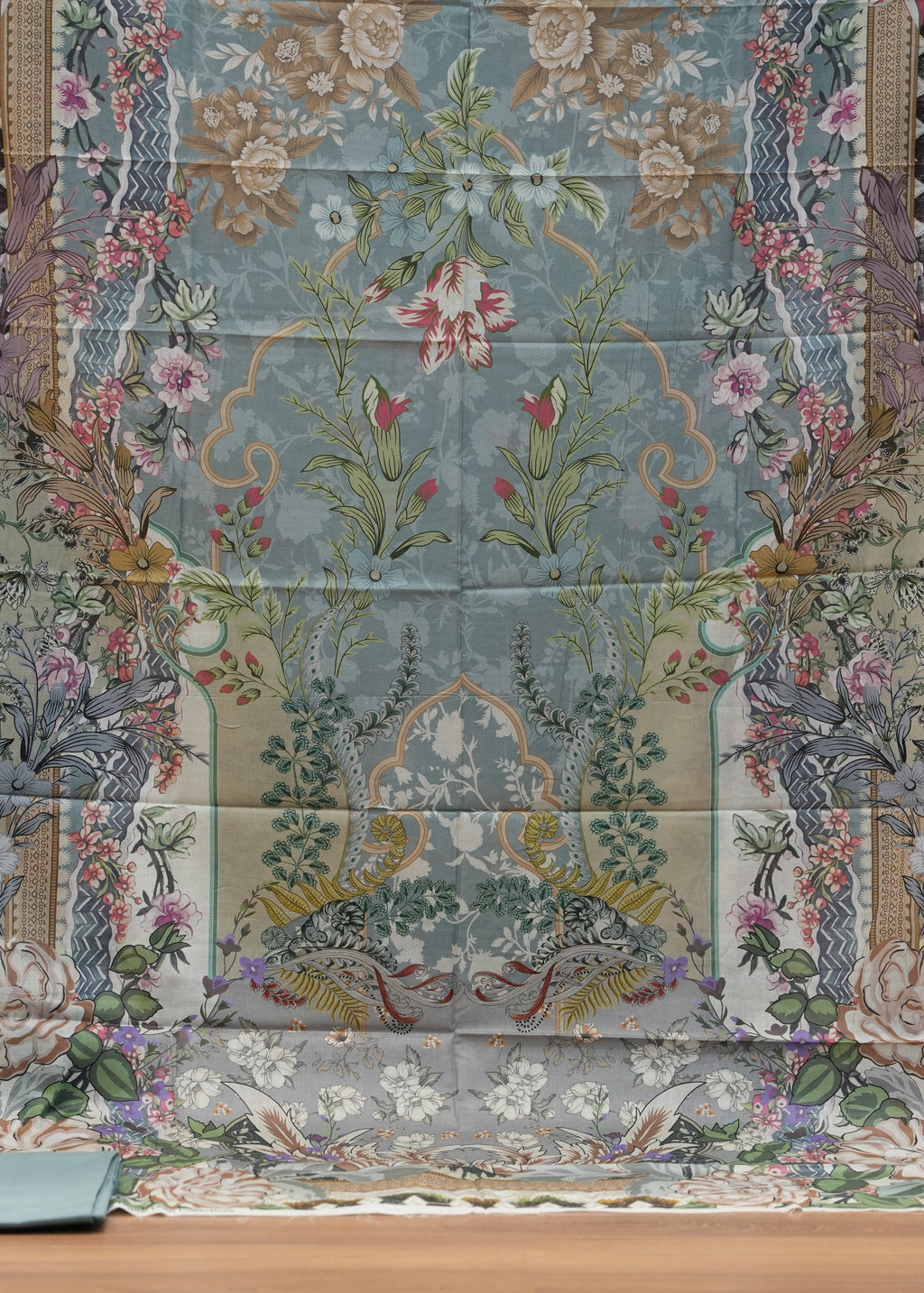Patchwork quilt with floral and nature-themed patterns on a wooden surface.
