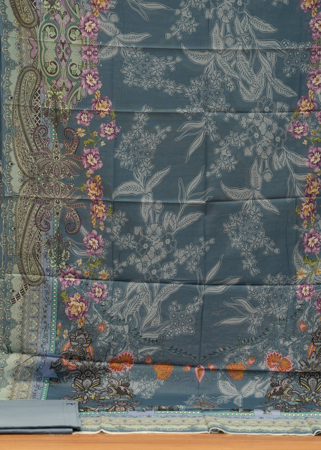 Collection of patterned fabrics with floral and paisley designs on a wooden surface.