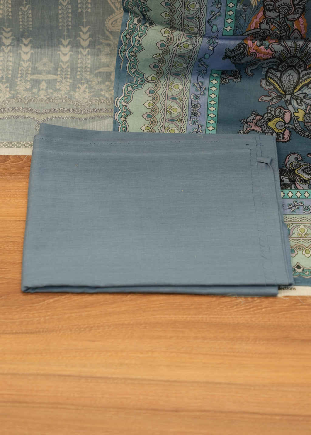 Folded gray fabric on a wooden surface with a patterned rug underneath