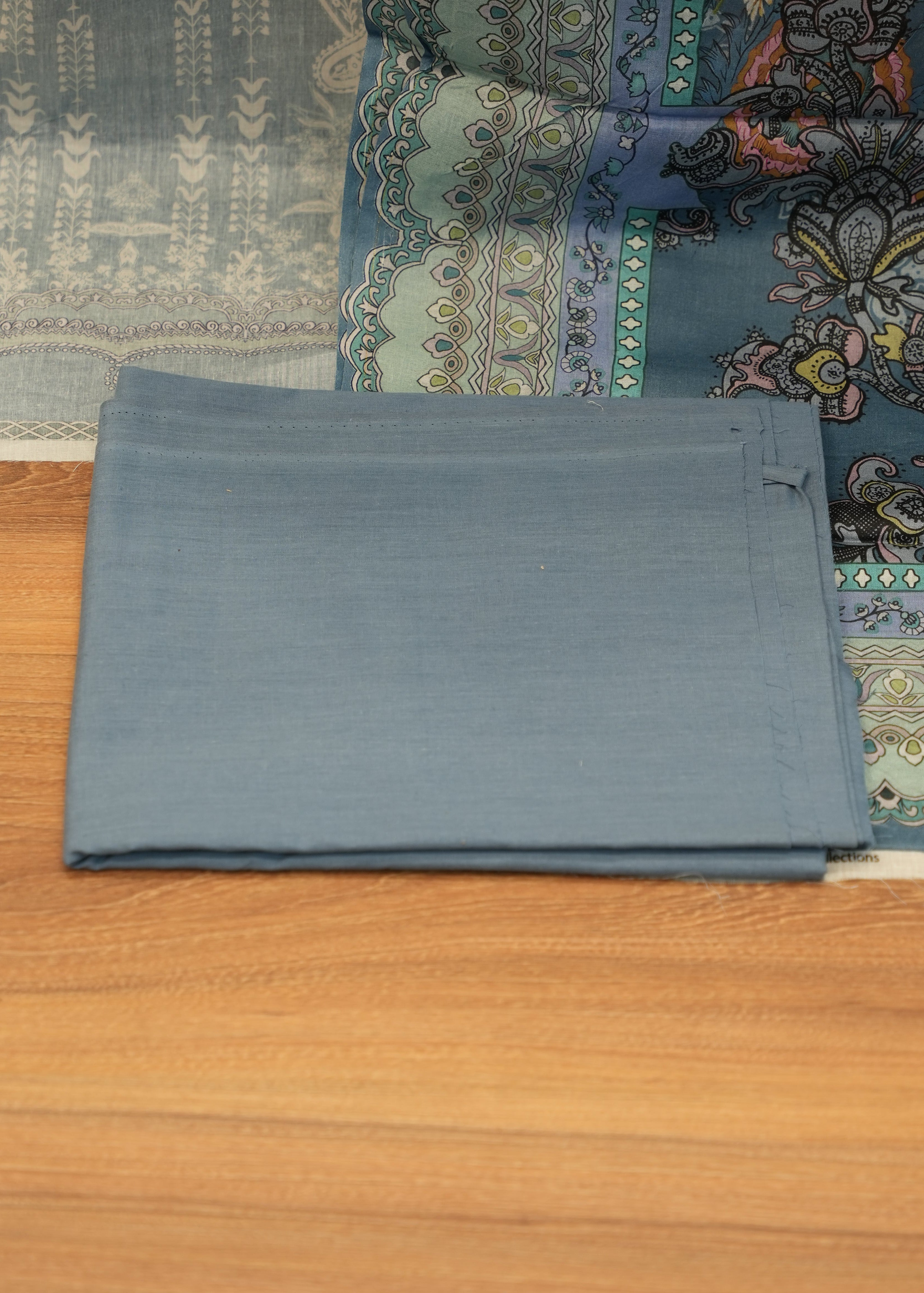 Folded gray fabric on a wooden surface with a patterned rug underneath