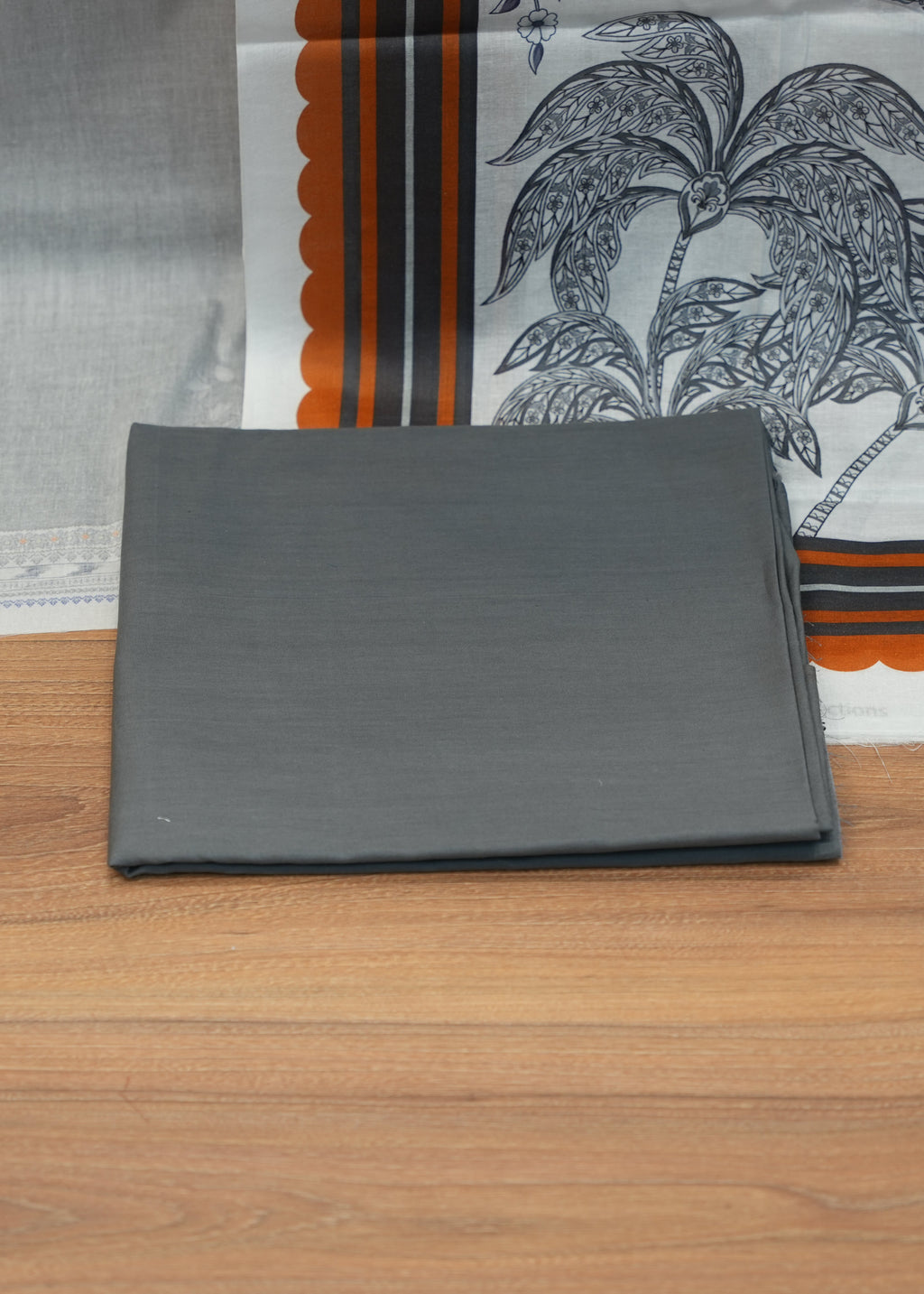 Gray fabric on a wooden surface with a patterned fabric in the background