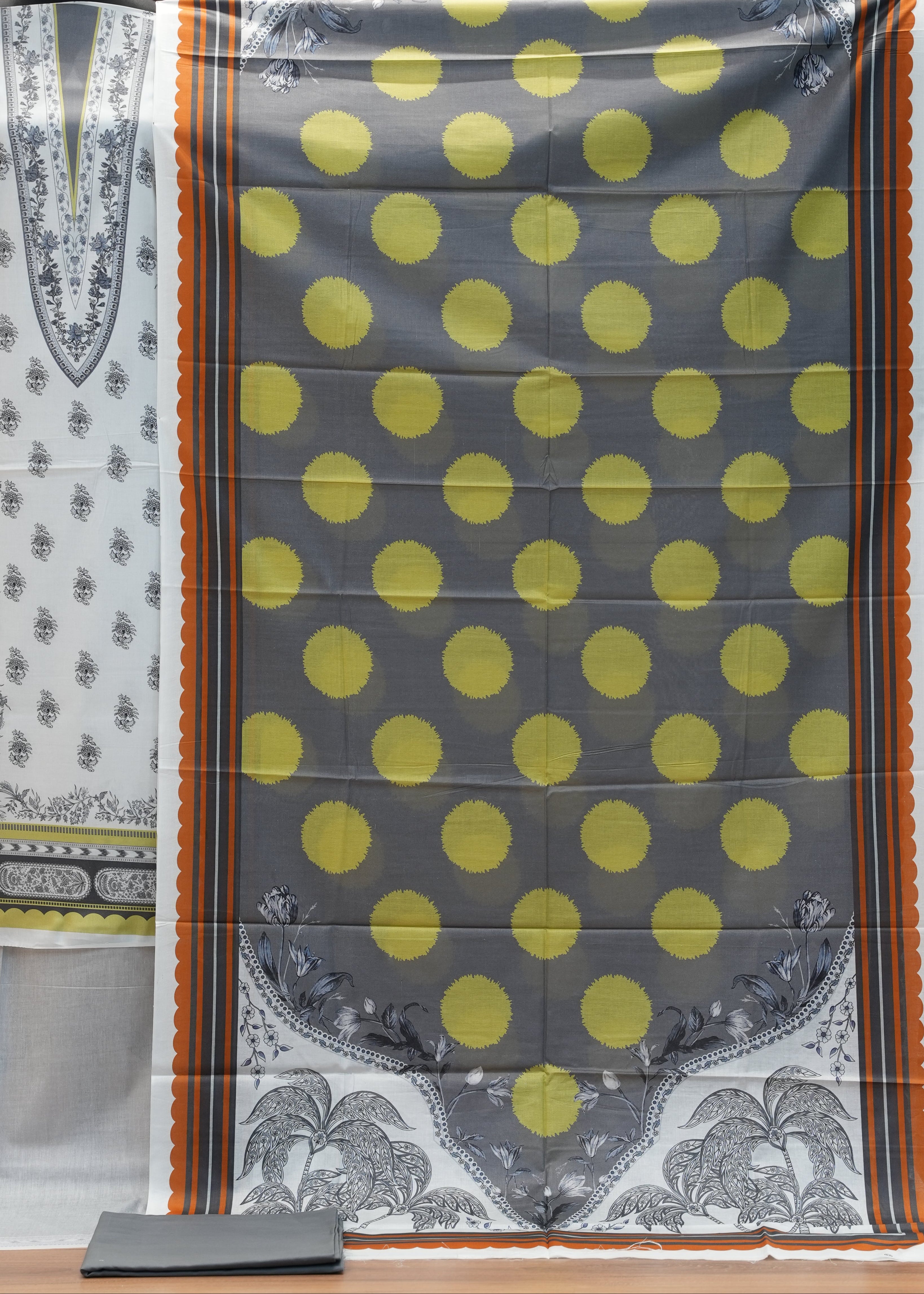 Decorative pillow with yellow polka dots on a gray background, displayed against a wooden panel.