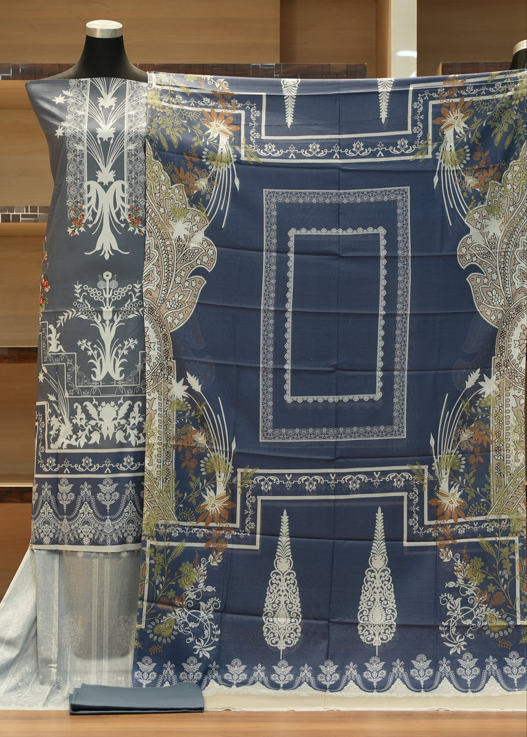 Decorative fabric with intricate patterns on a mannequin against a wooden background