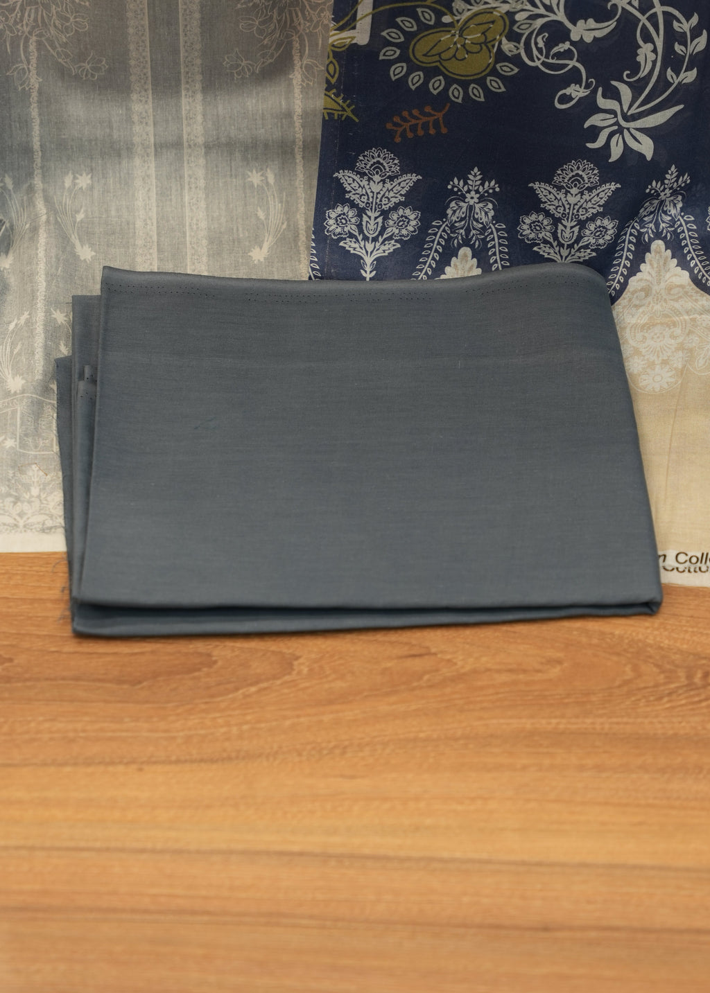Black folder on a wooden surface with a patterned fabric background