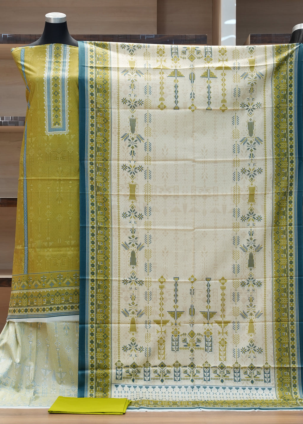 Traditional yellow and white saree with intricate patterns on a wooden hanger.