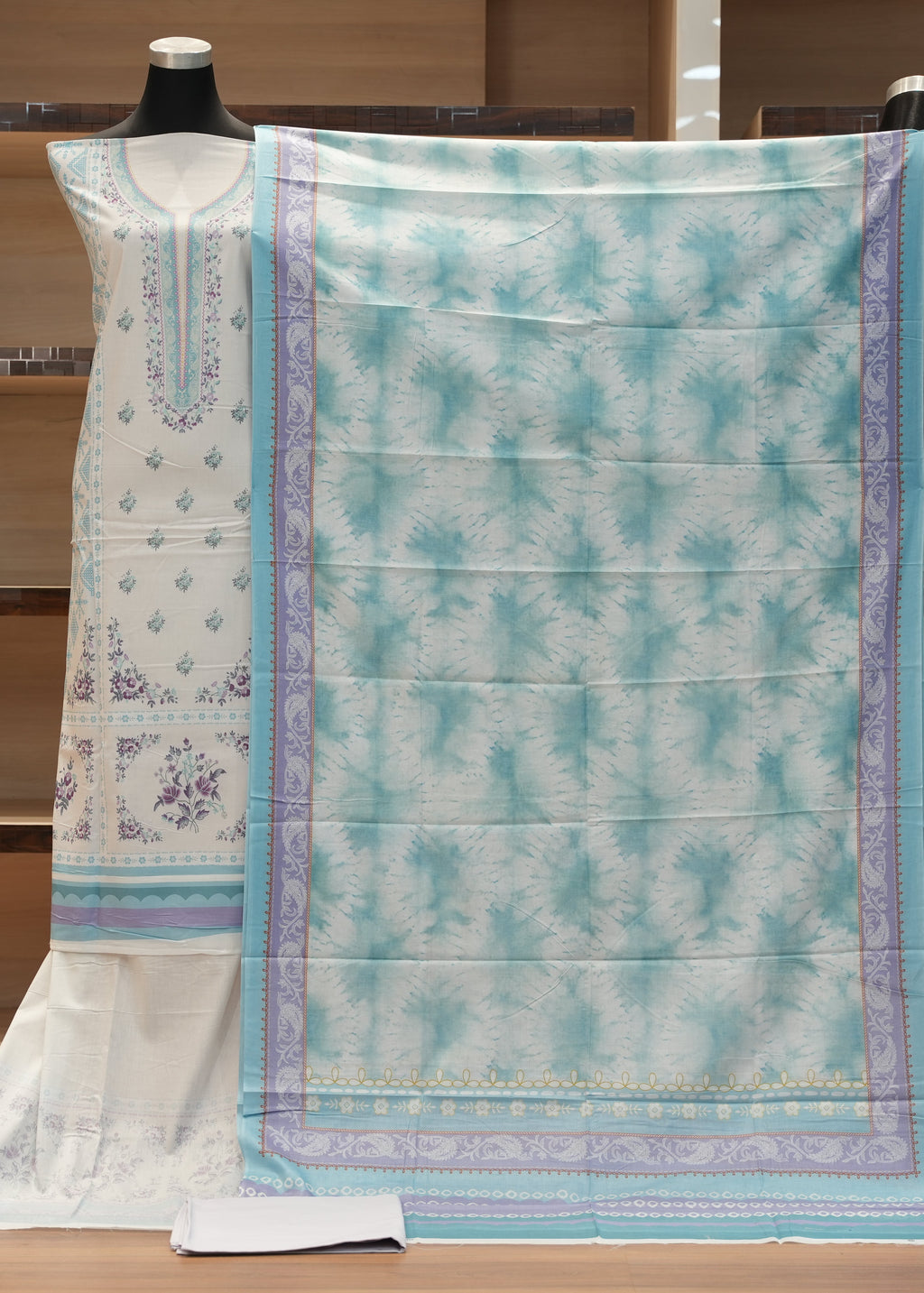 Traditional outfit with a white kurta and light blue dupatta on a wooden mannequin against a wooden background.