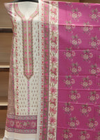 Pink fabric with floral patterns and white fabric with pink embroidery on a wooden surface.