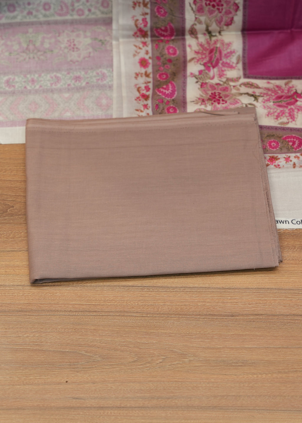 Brown fabric on a wooden surface with a floral patterned fabric in the background