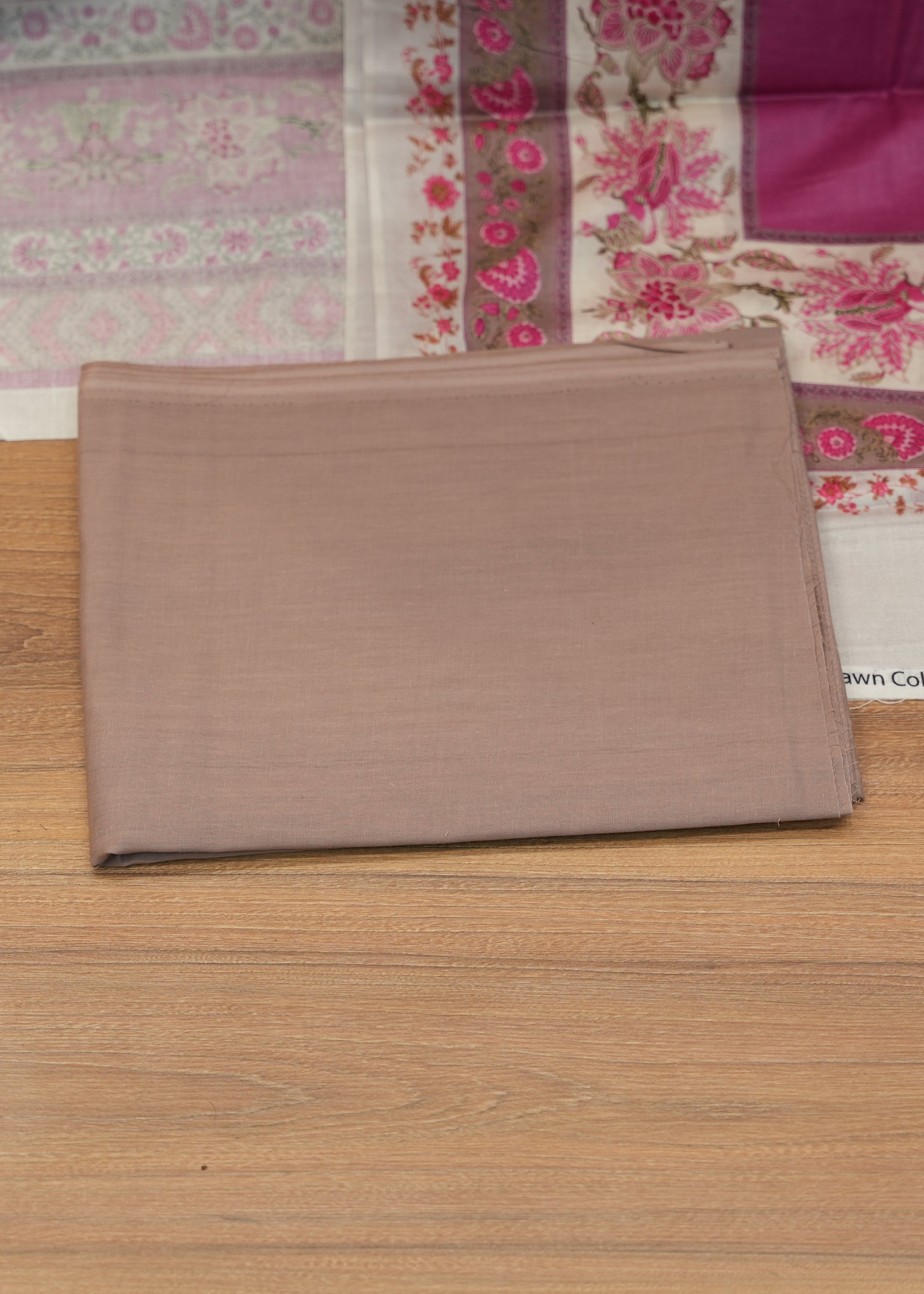 Brown fabric on a wooden surface with a floral patterned fabric in the background