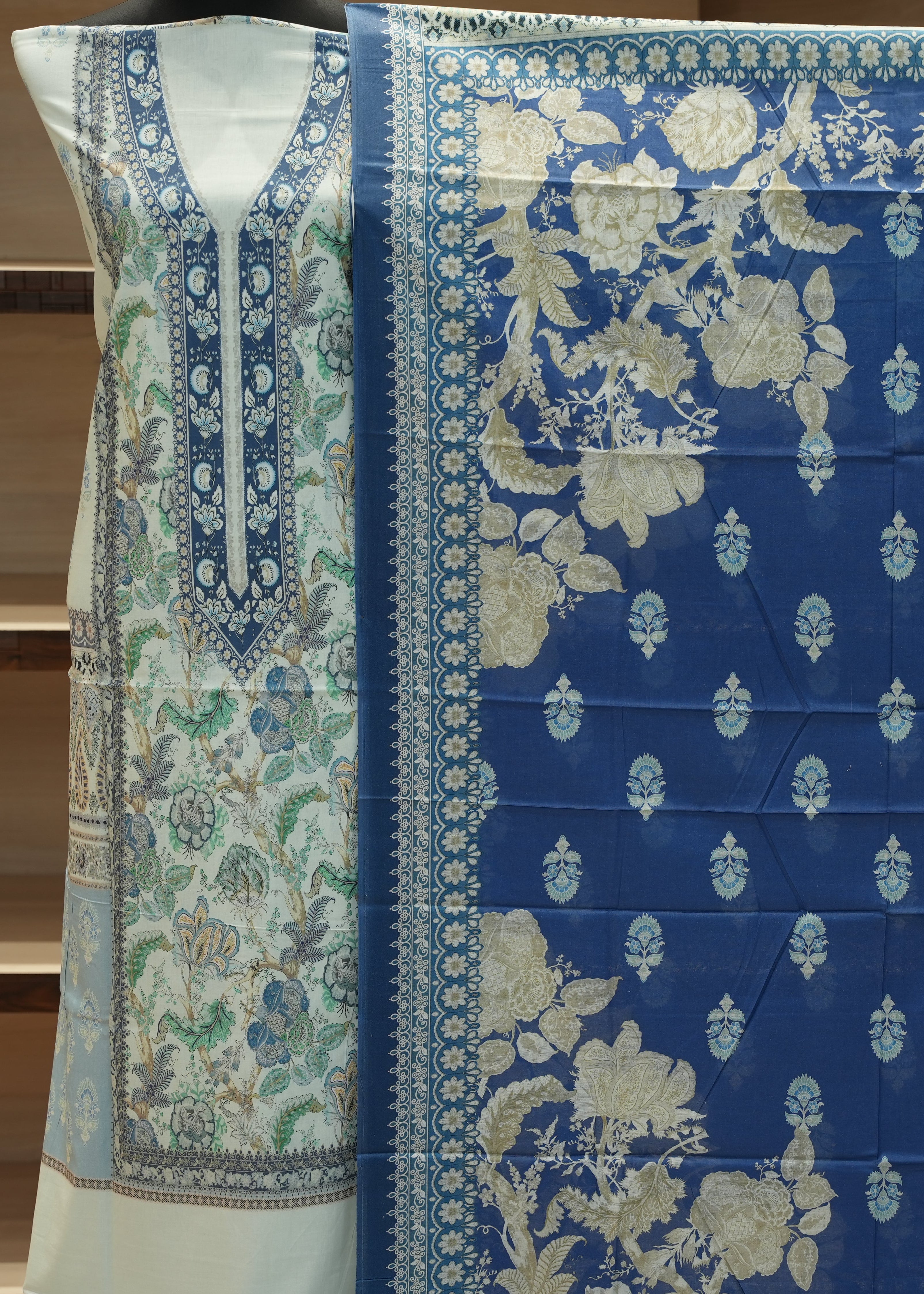 Blue and white floral patterned fabric with a green border on a wooden surface.