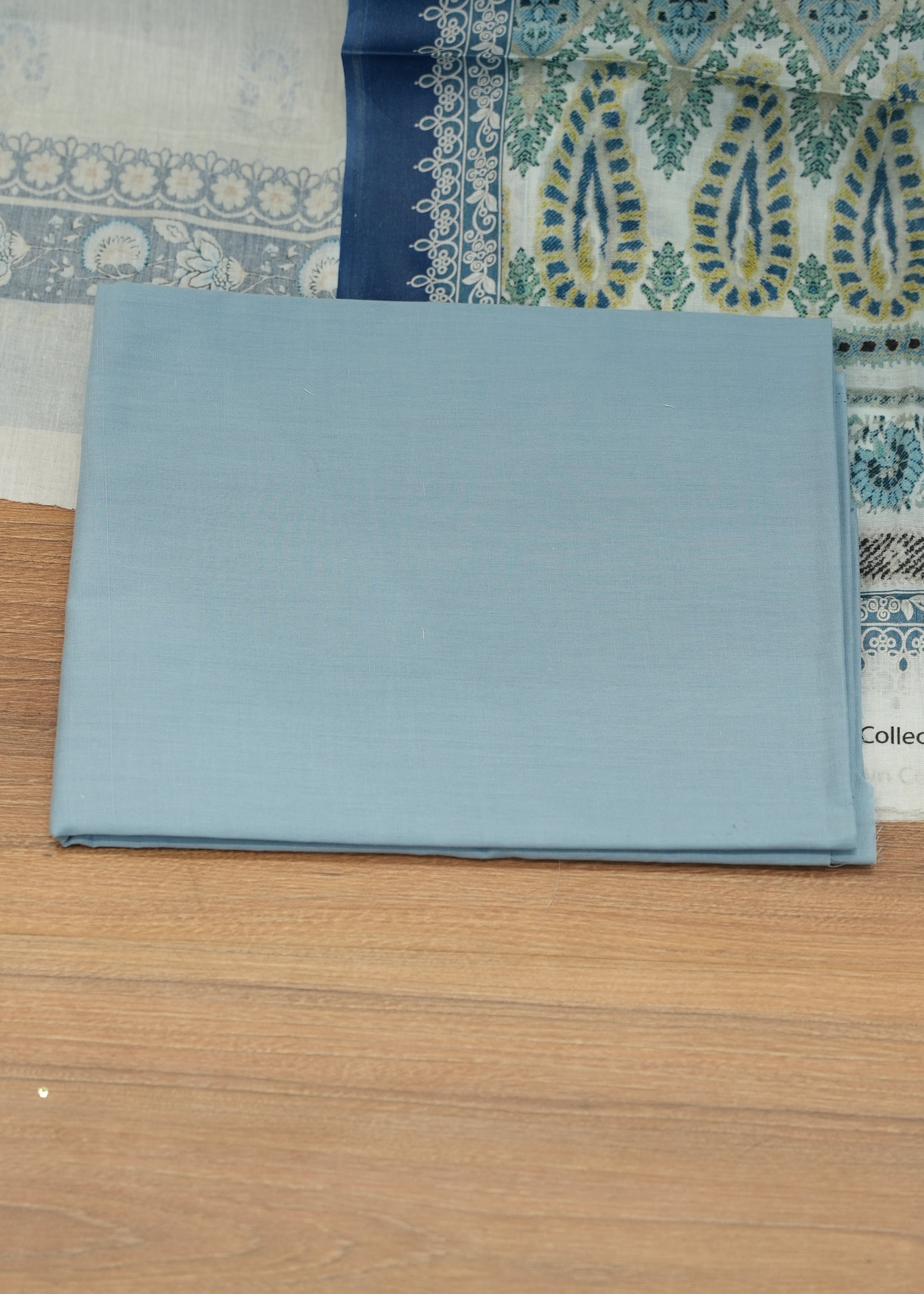 Light blue fabric on a wooden floor with a patterned rug underneath