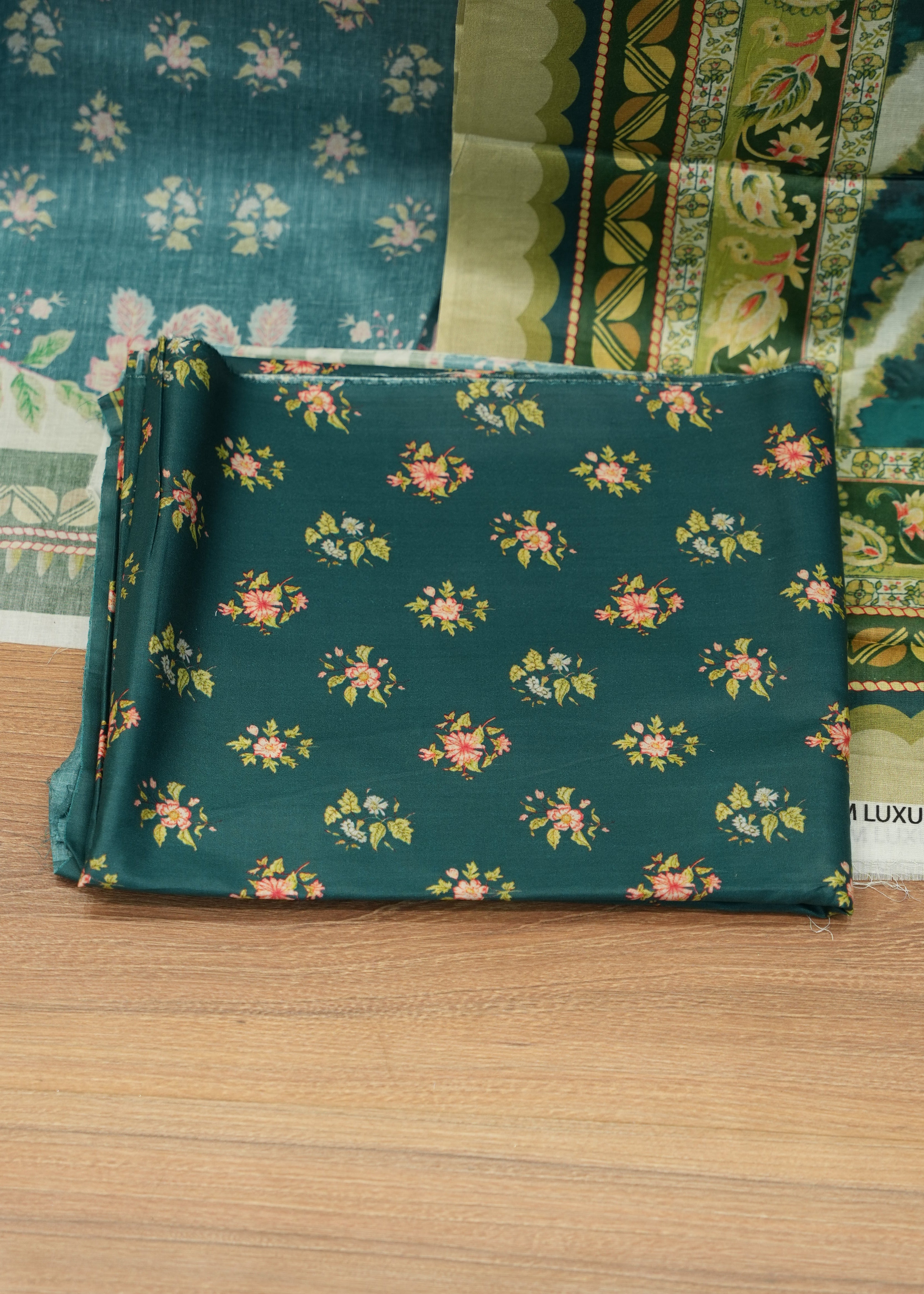 Roll of green floral fabric on a wooden surface