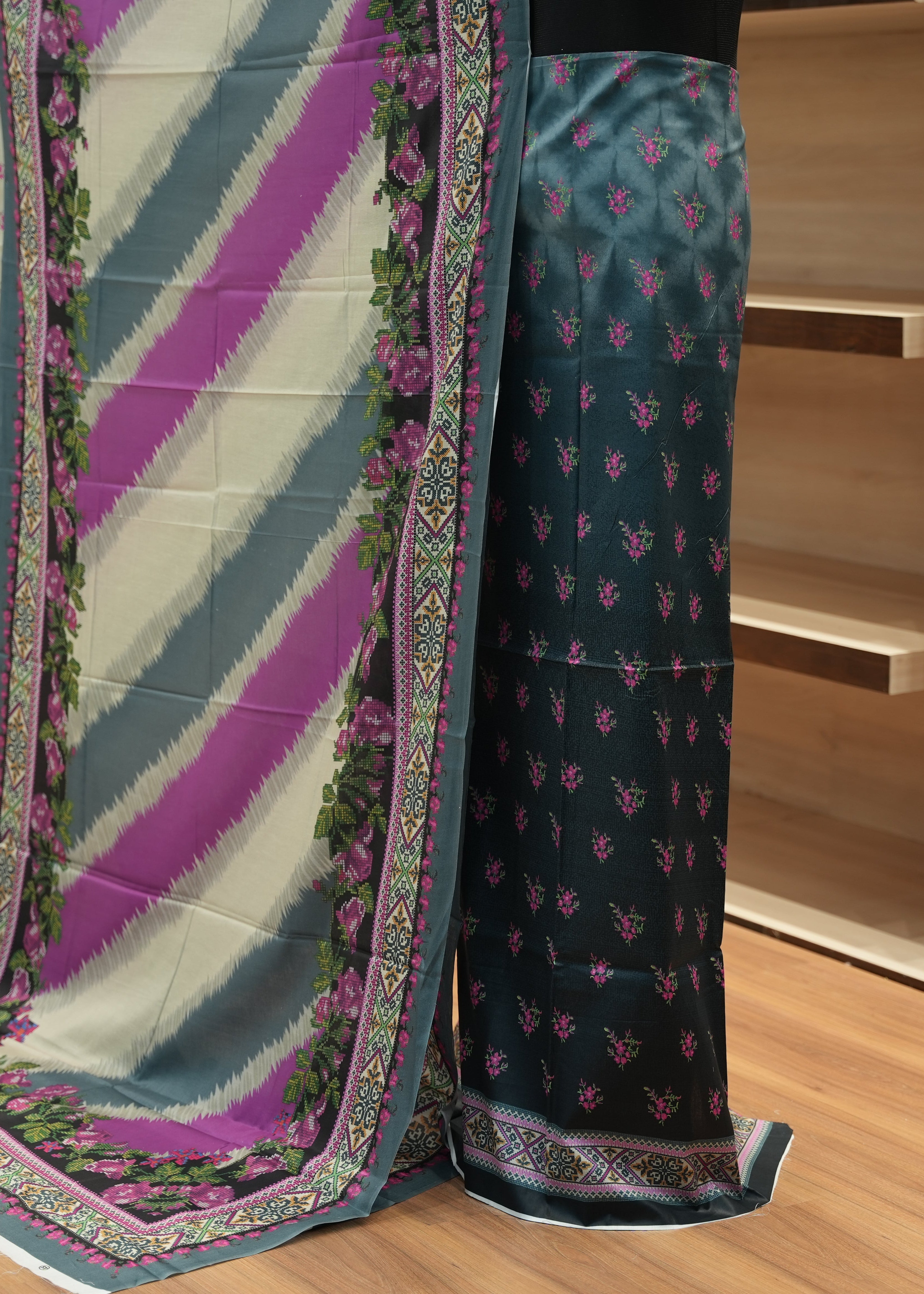Saree with a colorful border and patterned fabric on a wooden floor.